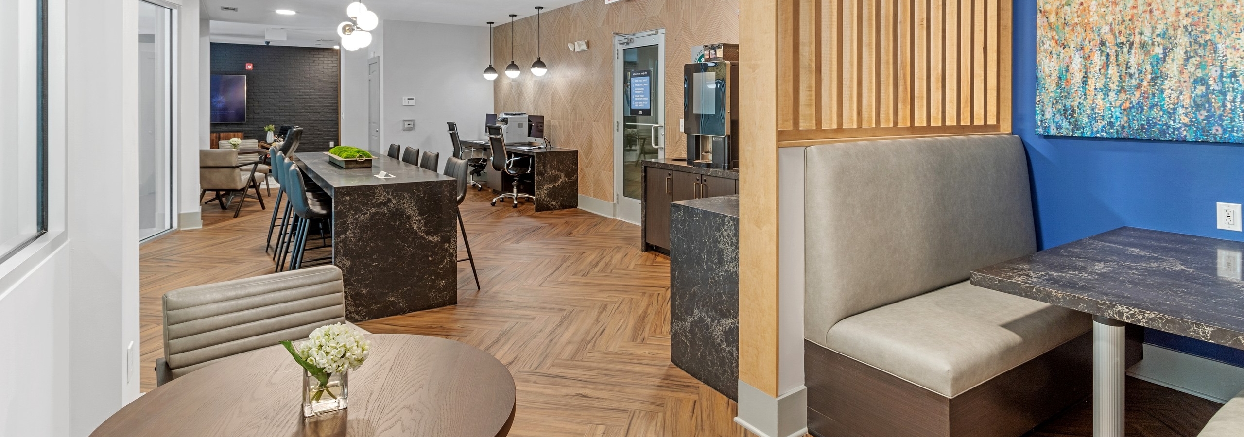 The business center at AMLI North Point with center island and chairs and computer stations with wood floors and booth seat