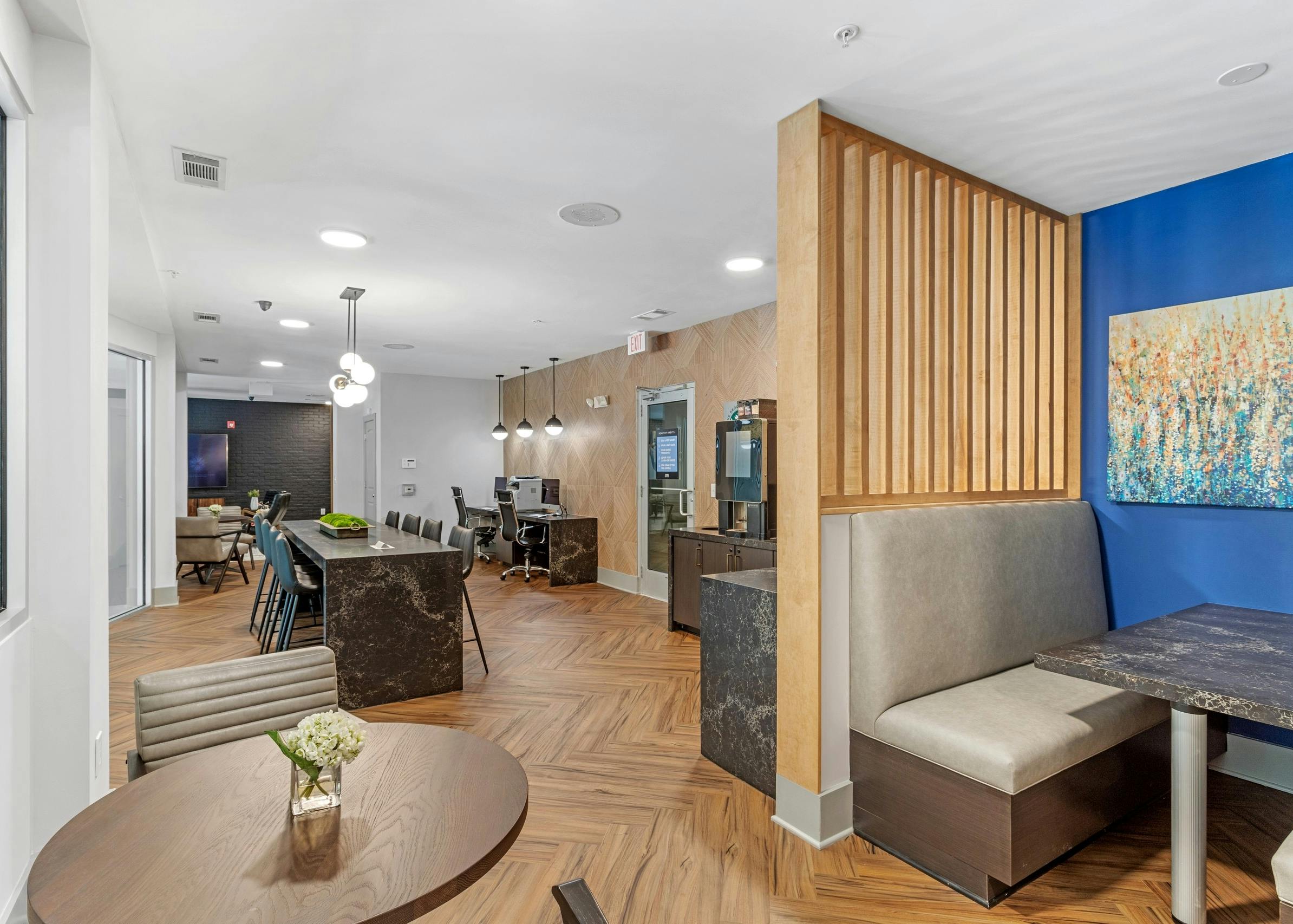 The business center at AMLI North Point with center island and chairs and computer stations with wood floors and booth seat