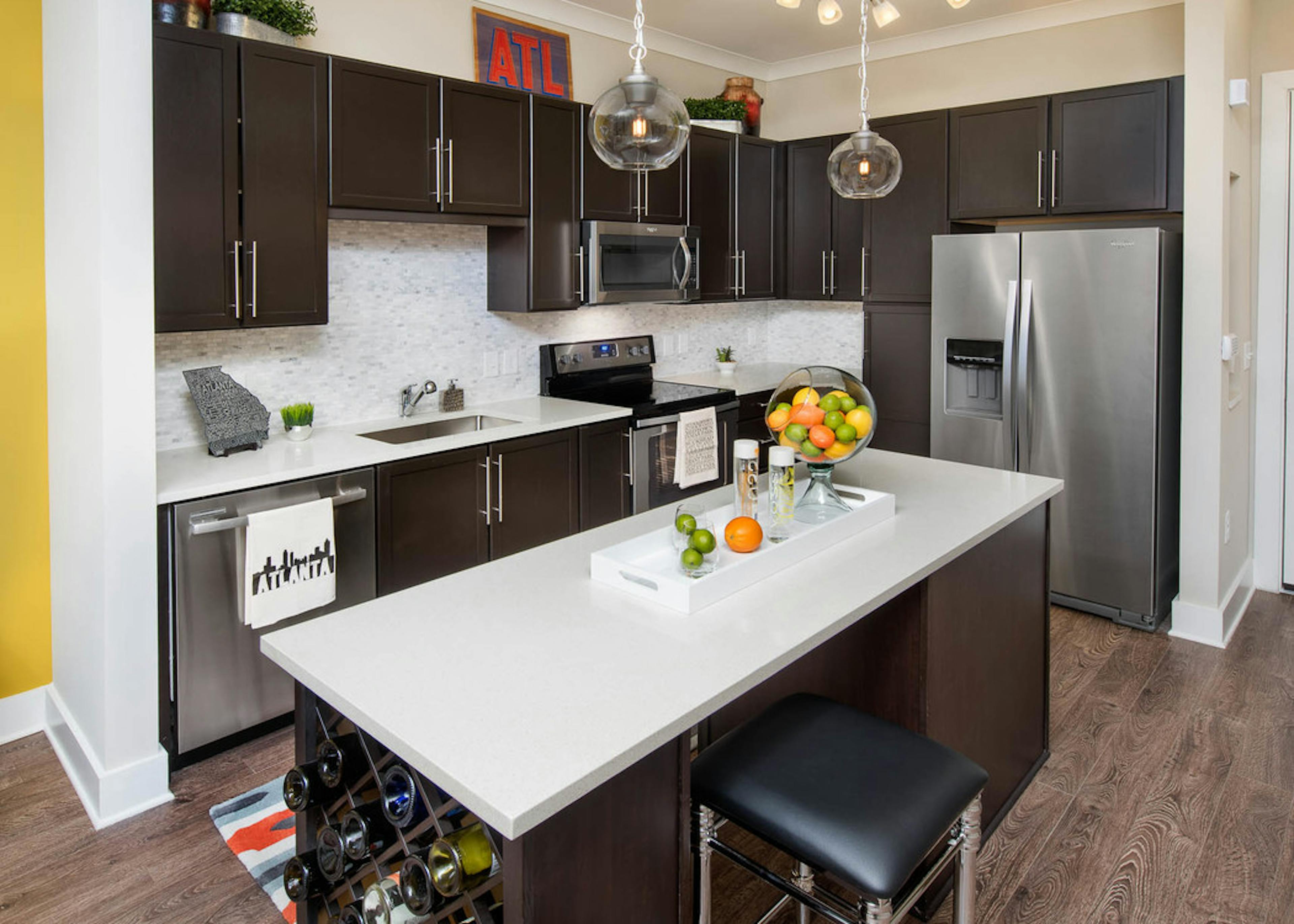 Interior of AMLI Buckhead kitchen with dark cabinets and sleek white countertops with stainless steel appliances and island