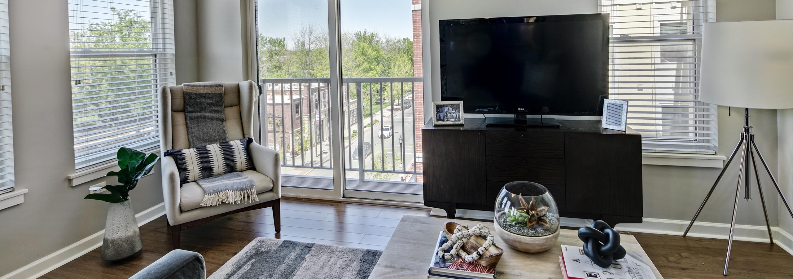 AMLI Evanston apartment living room with dark flooring surrounded by windows with door to balcony showing daytime view