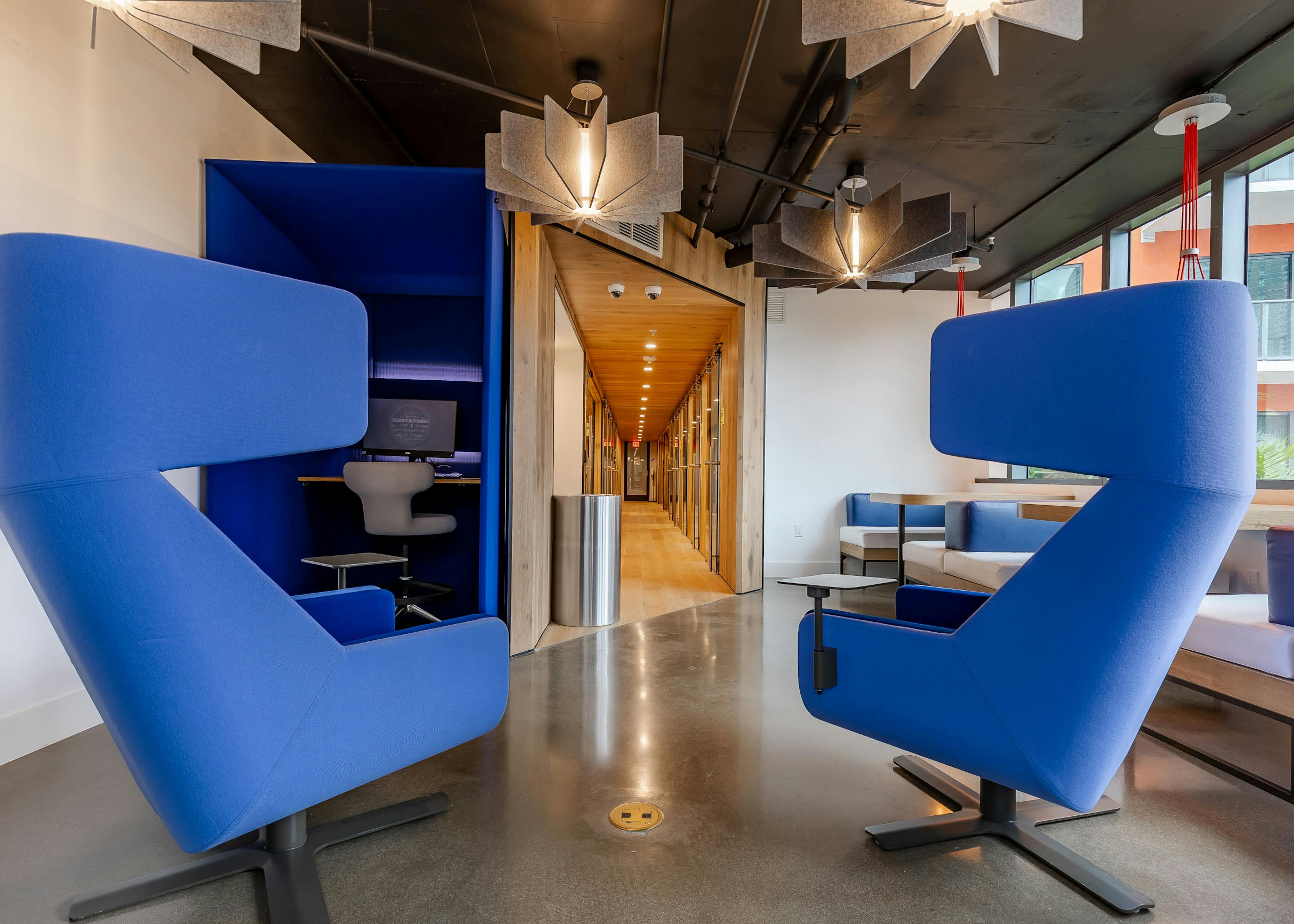 Interior view of AMLI Midtown Miami coworking space with blue modern armchairs and built in desks and view of long hallway  