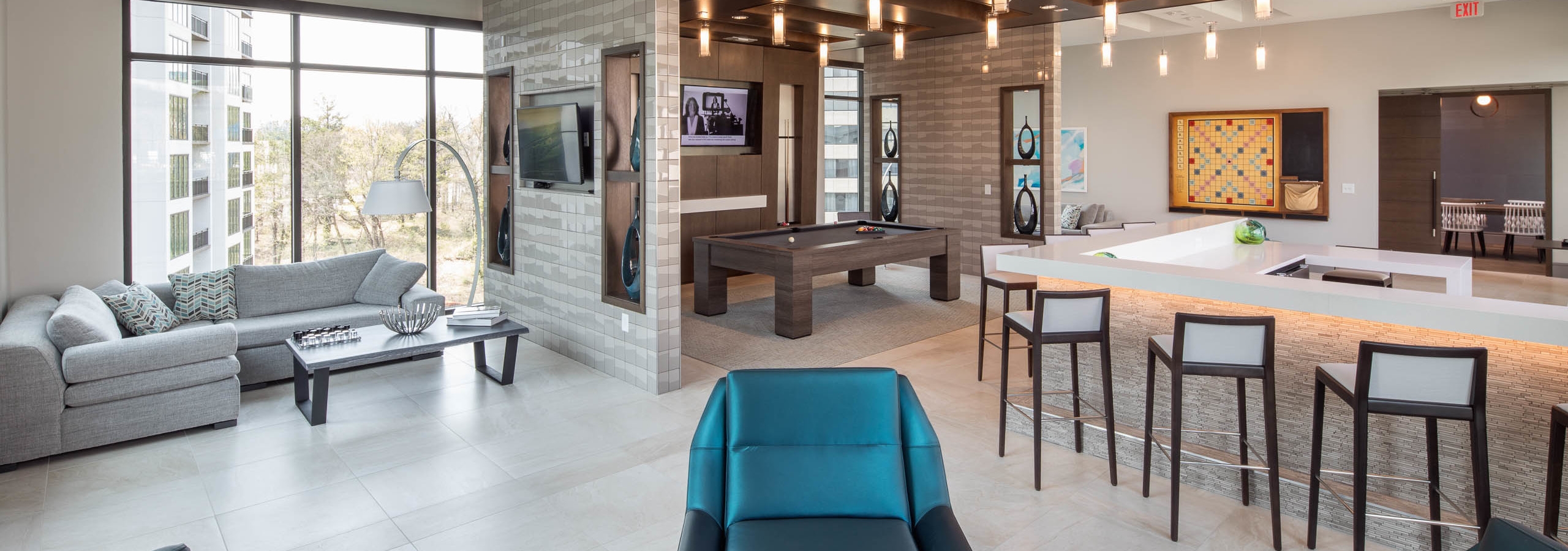 Clubroom at AMLI 3464 with floor to ceiling windows and a variety of seating options with a billiard table and a large TV