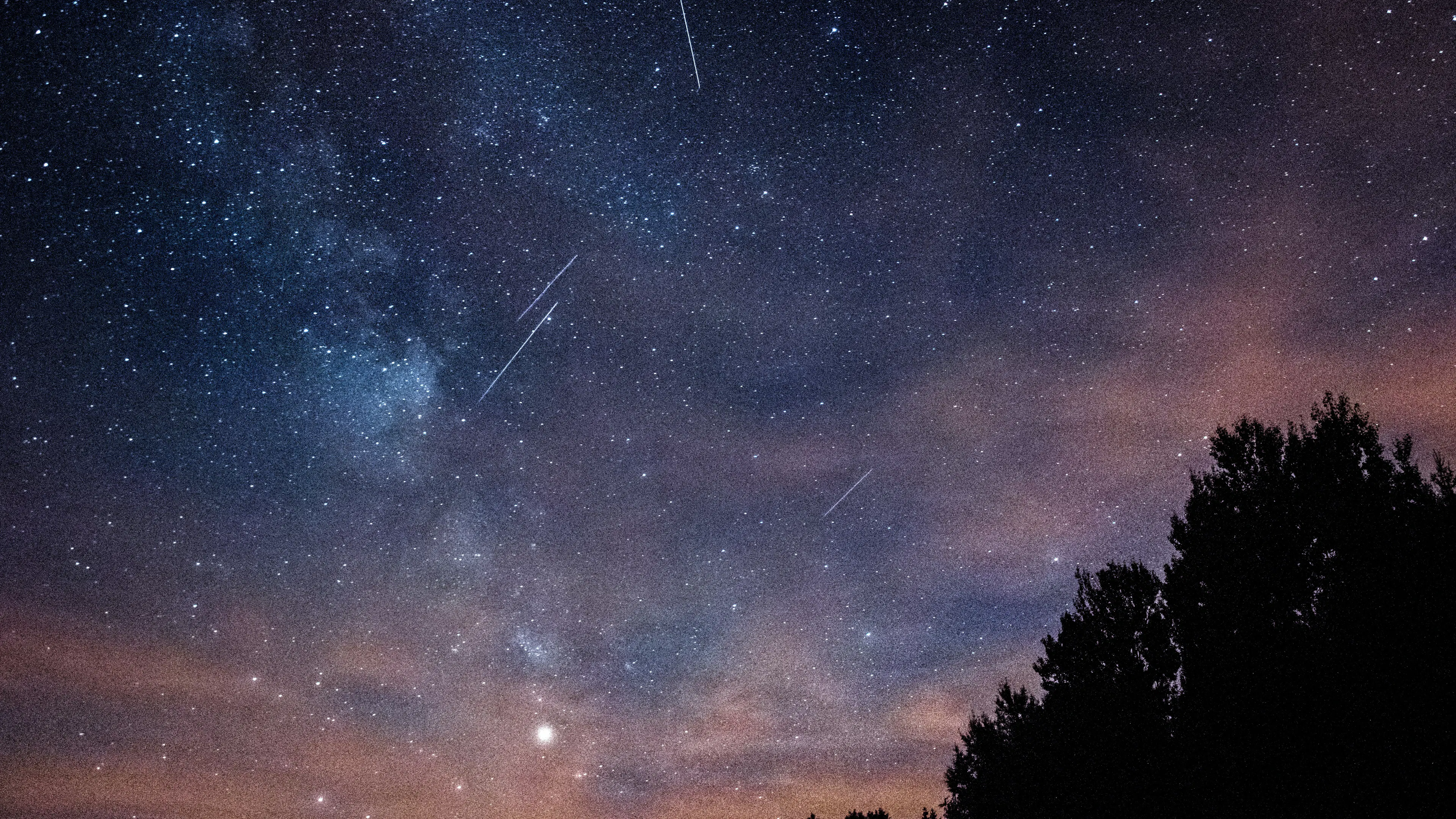 A starry night sky with a few meteors streaking across the Milky Way