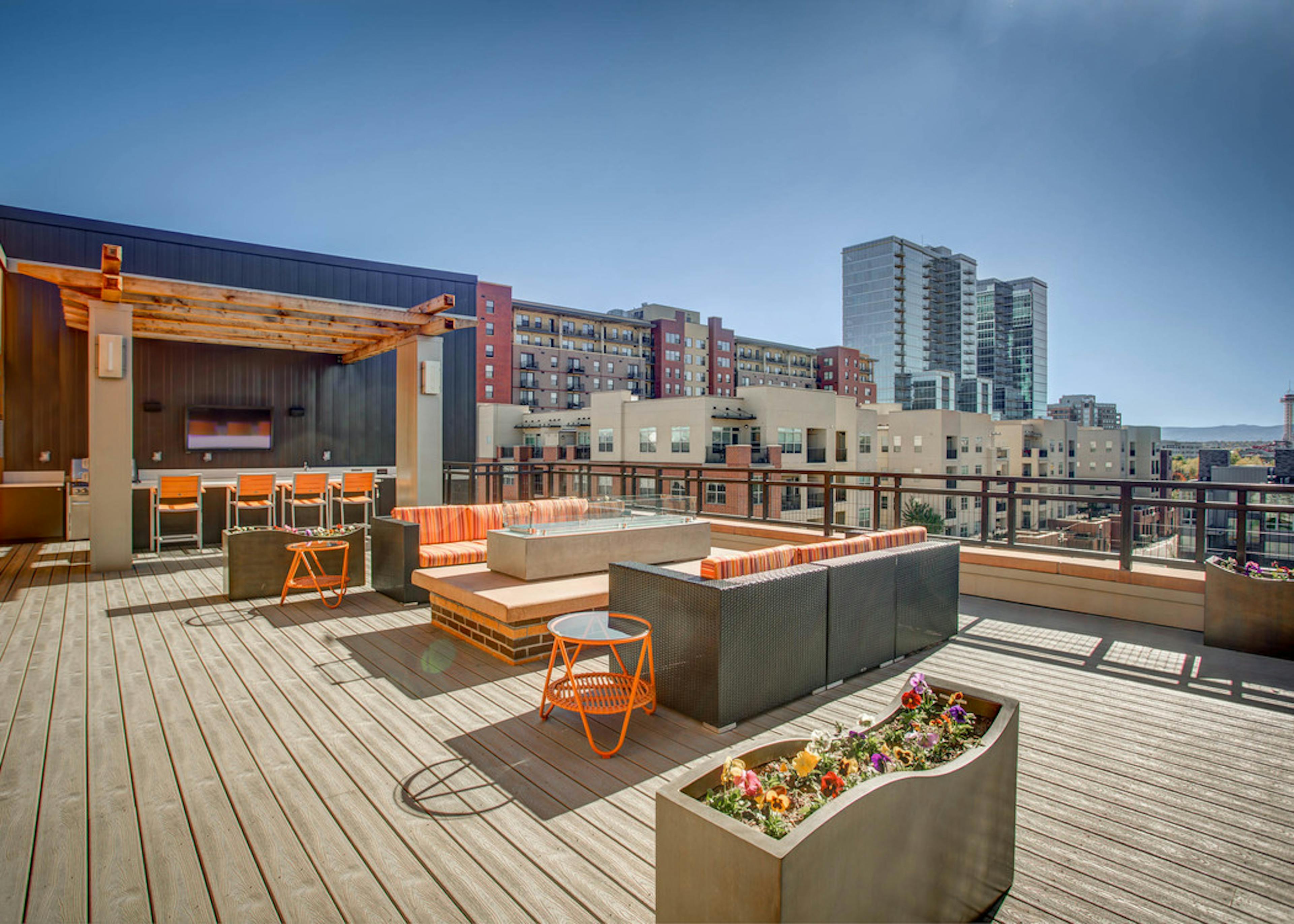 Exterior view of the rooftop deck at AMLI Riverfront Park with fire pit and several seating areas and view of Denver skyline