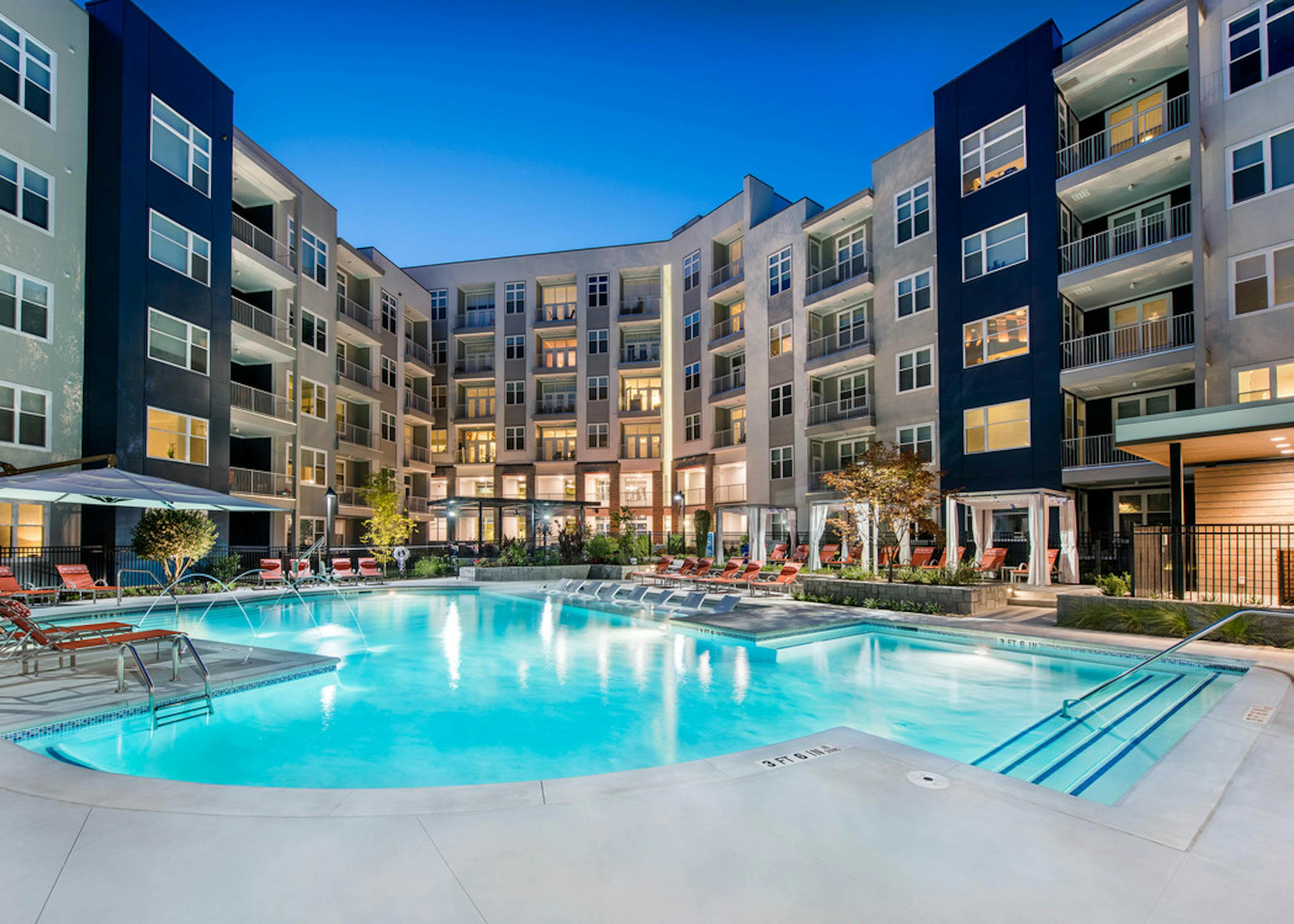 Angle of AMLI Buckhead pool facing the building exterior with surrounding orange lounge chairs on the pavement