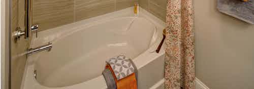 Interior view of an AMLI Deerfield apartment community bathroom with a large white garden tub and neutral decor