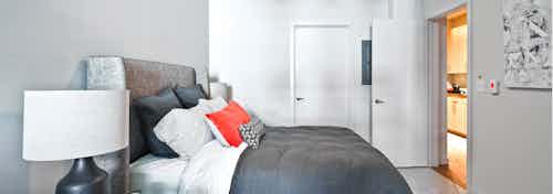Apartment bedroom at AMLI South Lake Union with a queen-sized bed and bedside table with a lamp and view of the walk in closet