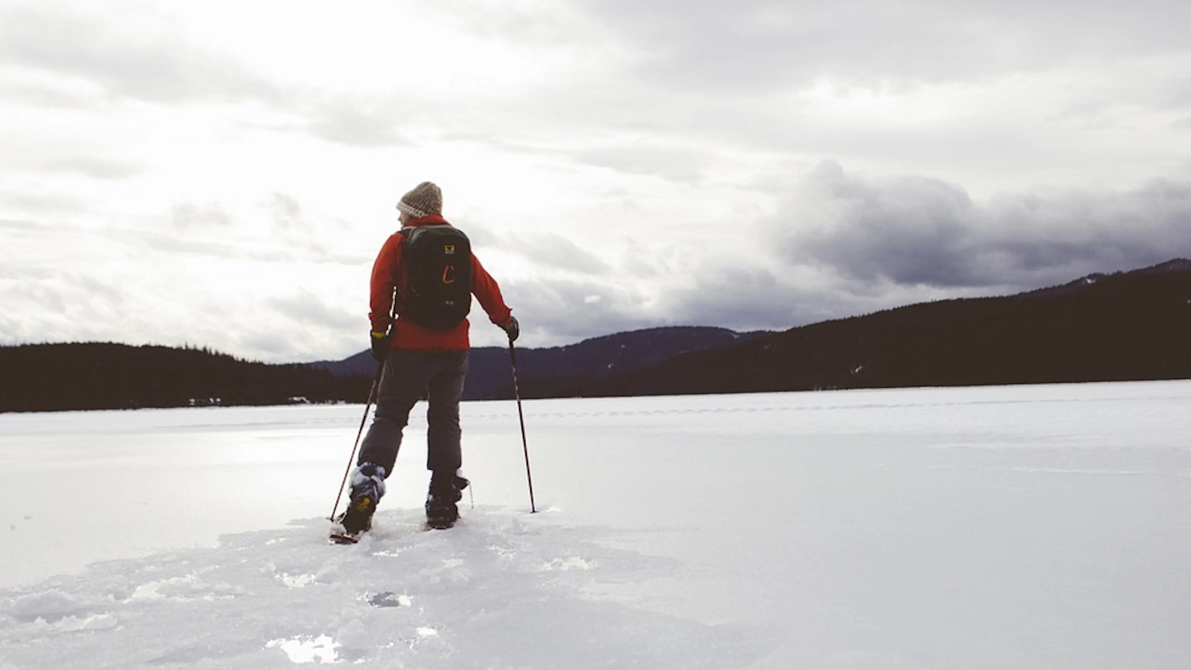 A lone skier on Nordic skis heading off into a snow covered meadow