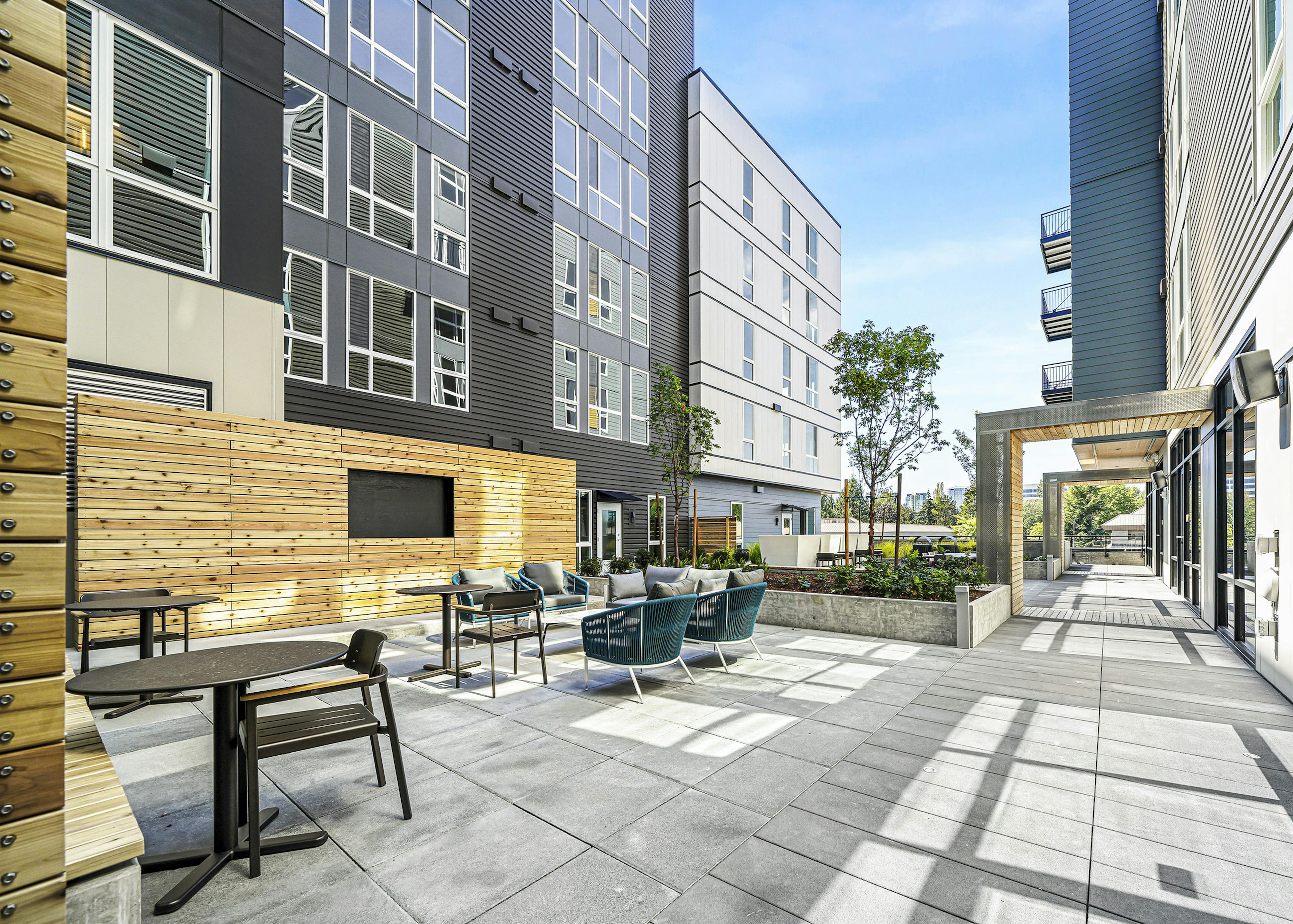 Daytime view of AMLI Spring District apartments landscaped courtyard with seating and large tv built into large wood wall 