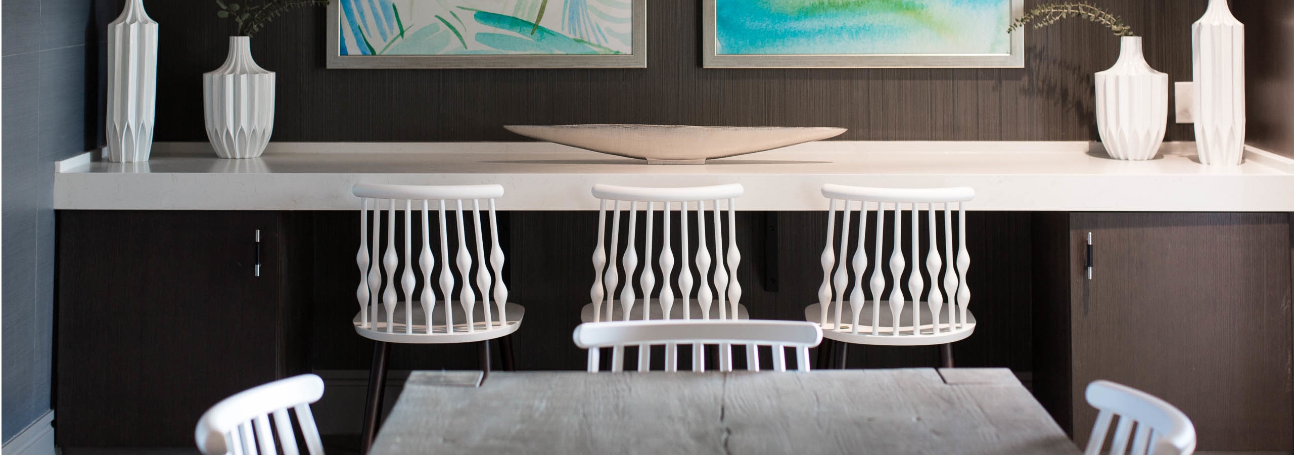 Table and counter seating area in the AMLI 3464 resident lounge with dark wood cabinets and white decorative vases