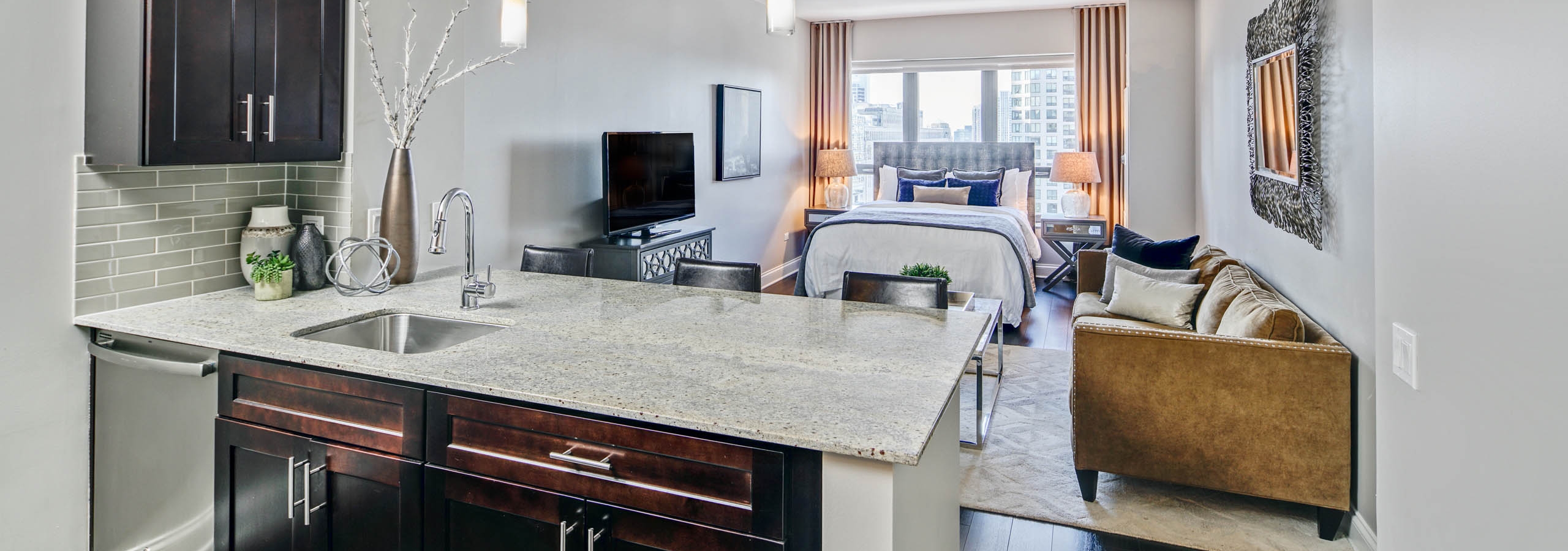 AMLI River North guest suite with a studio layout including a luxurious kitchen and living area with bed visible in back