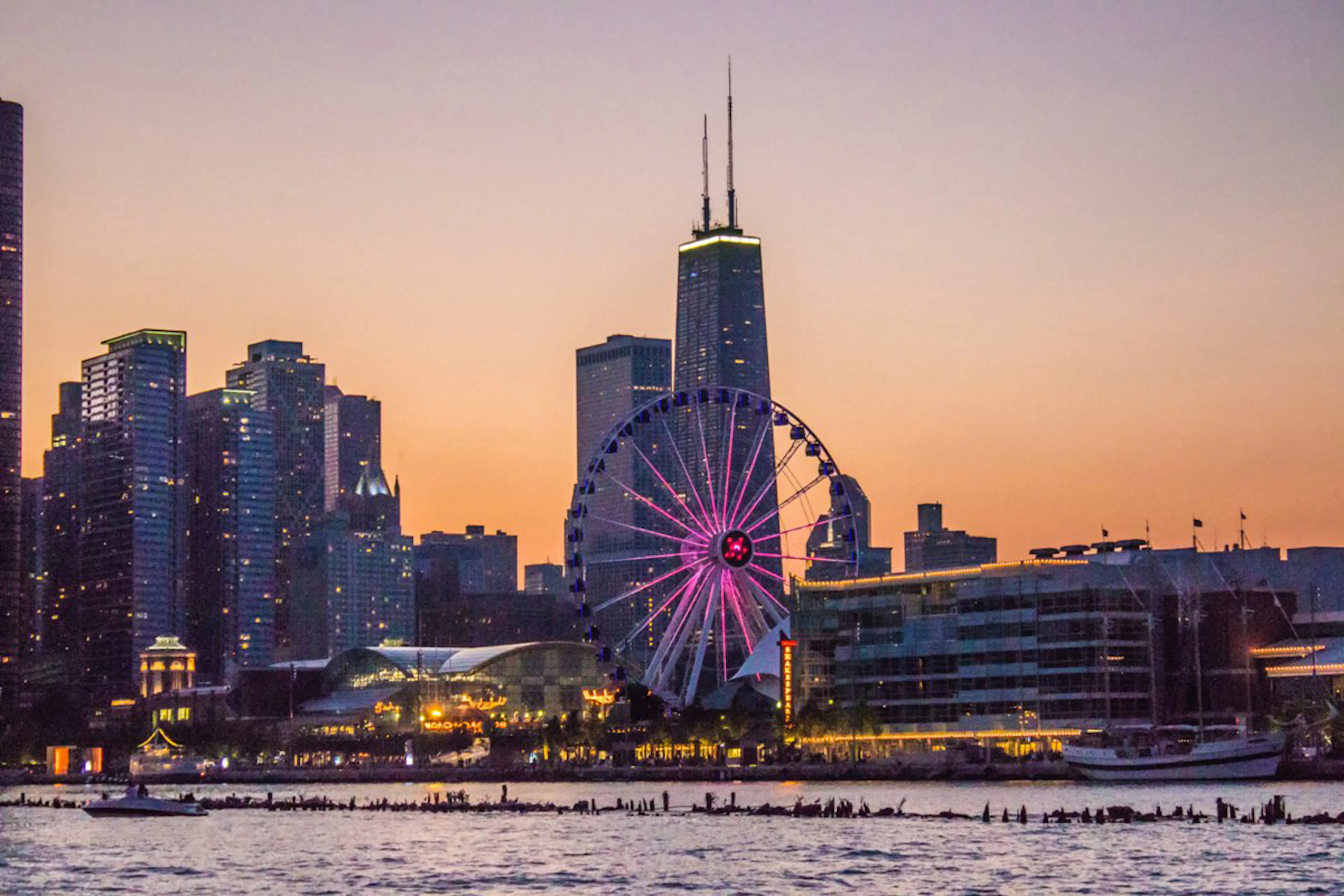 View of Navy Pier and its Ferris wheel against the Chicago skyline at dusk from the water of Lake Michigan
