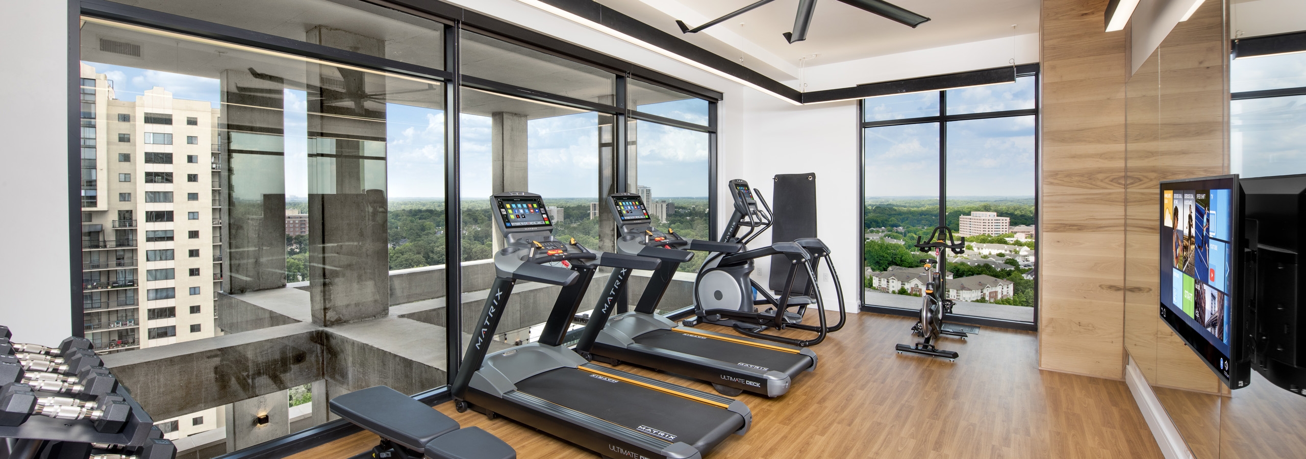 Upstairs AMLI Lenox exercise room with treadmills and weights and fitness on demand with floor to ceiling windows