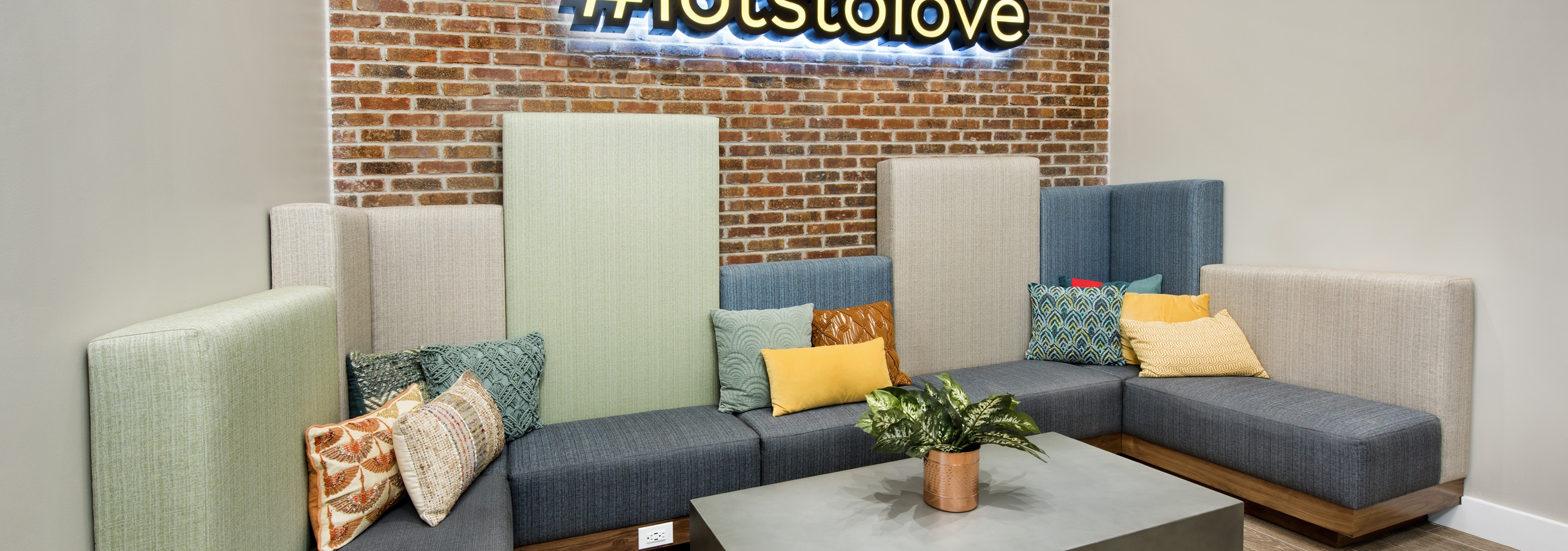 AMLI Decatur dog lounge with comfortable seating and table with plant on it with a #lotsoflove sign hanging on brick wall