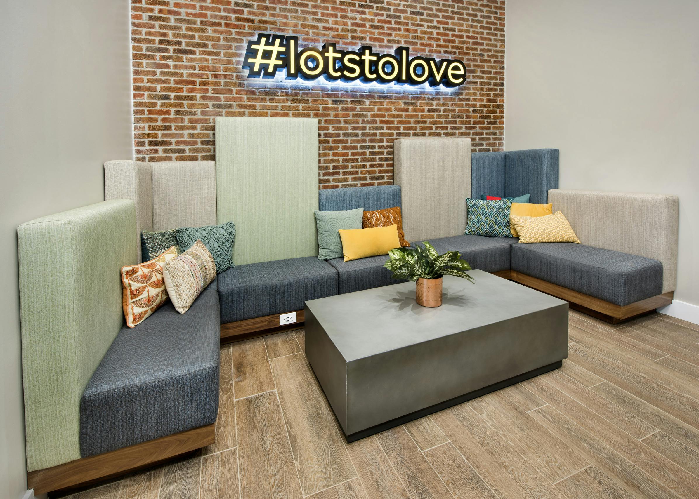Interior dog lounge at AMLI Decatur with comfortable seating, table with plant and #lotsoflove sign on brick wall