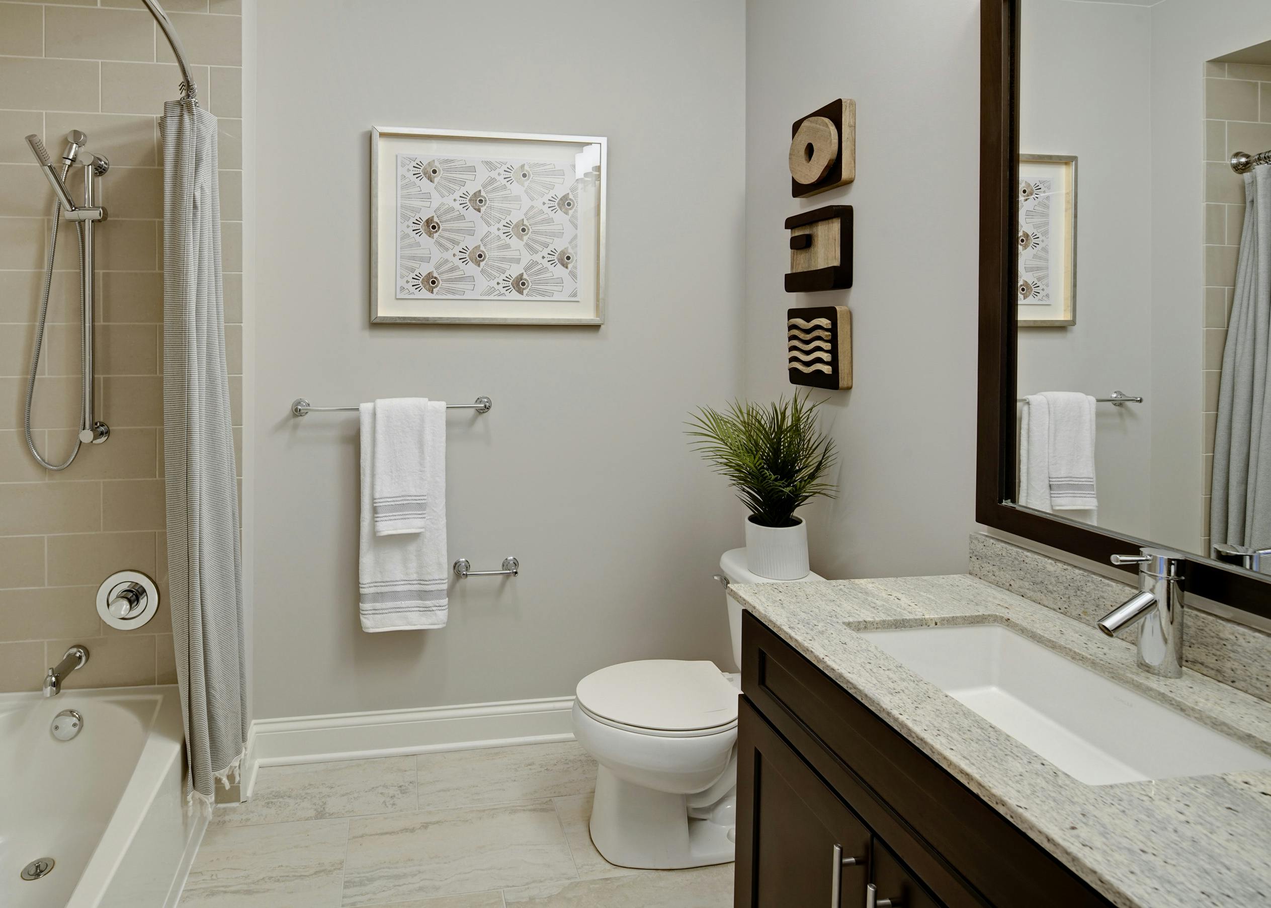 Granite vanity sink in AMLI River North apartment bathroom with modern decor and white towels hanging above light tile floors