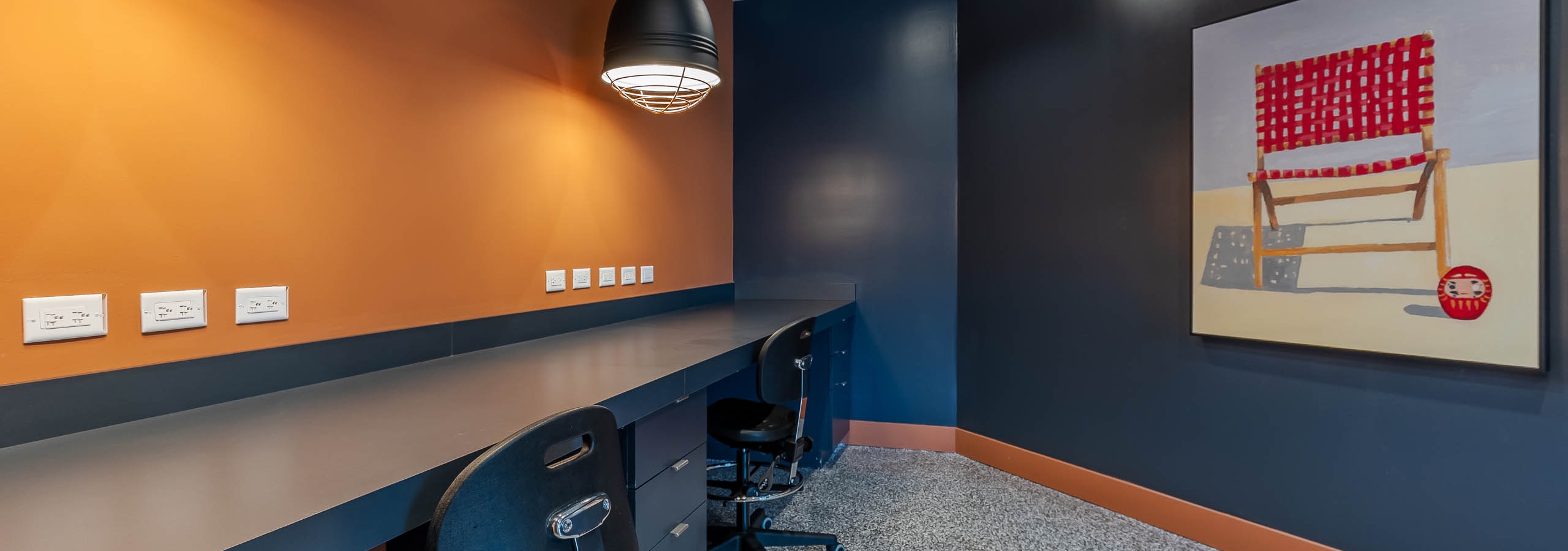 AMLI Park West apartments makers space with a built in desk and chairs navy with blue wall with beach chair artwork