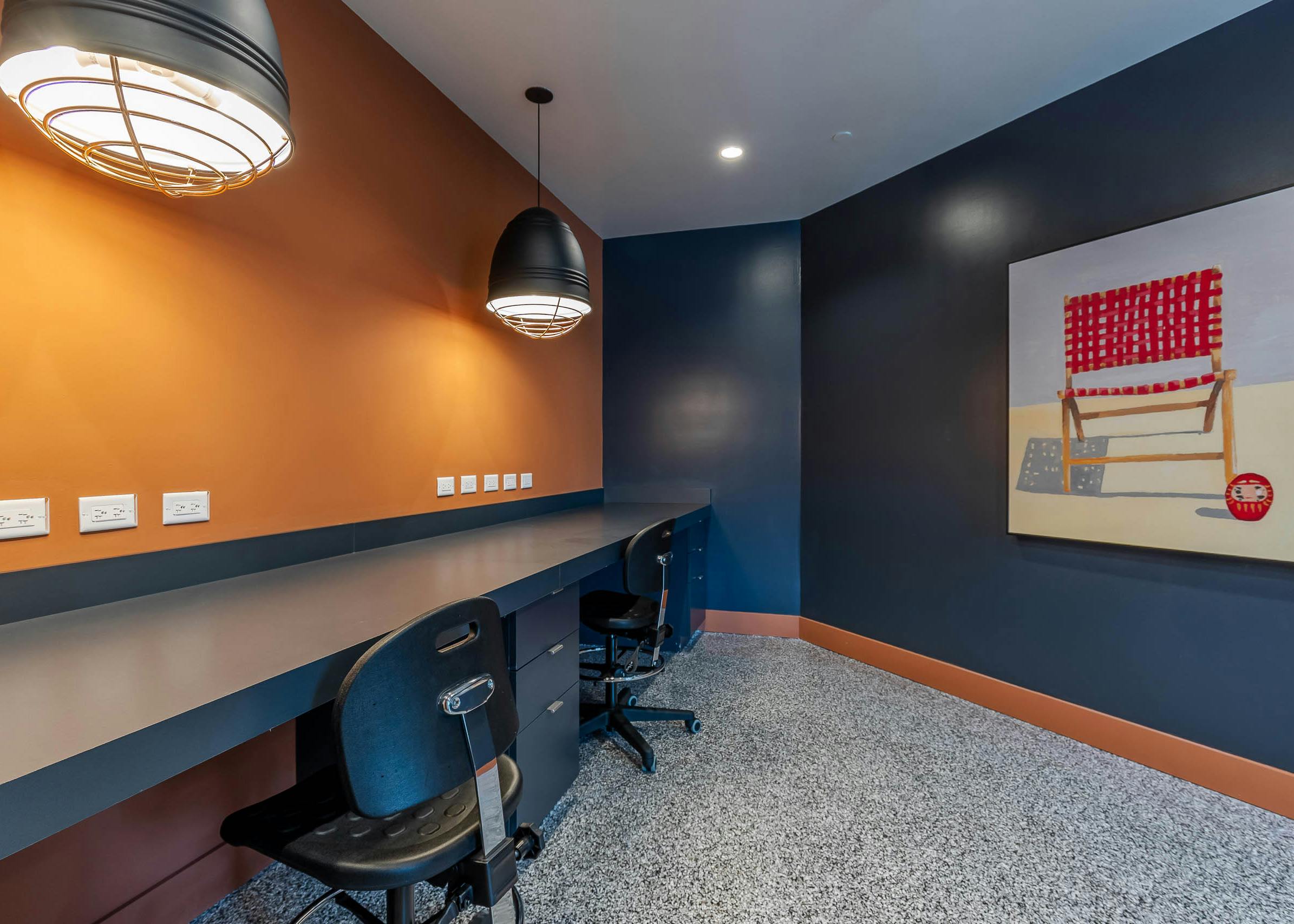 AMLI Park West apartments makers space with a built in desk and chairs navy with blue wall with beach chair artwork