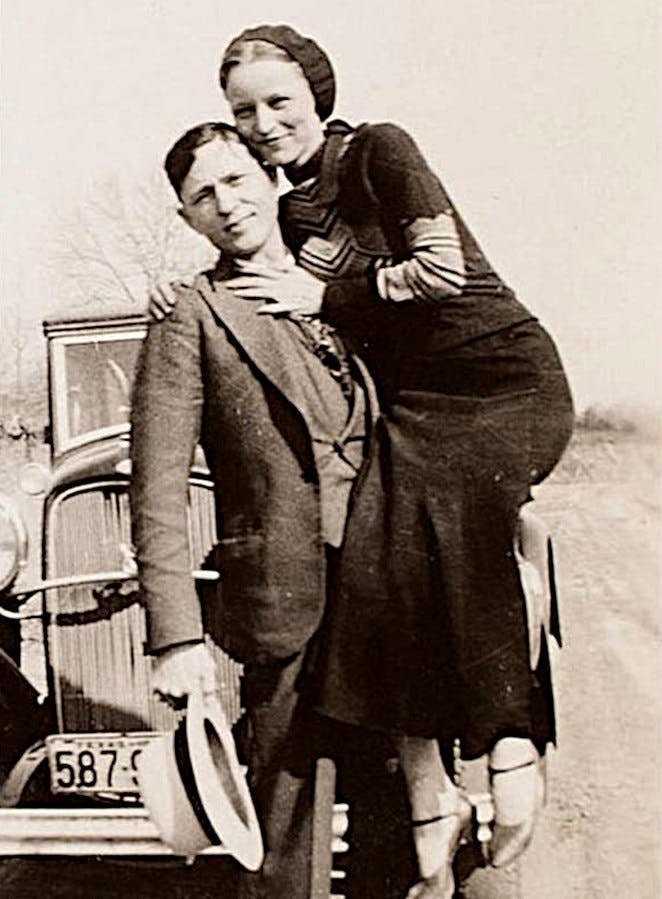 Clyde Barrow and Bonnie Parker smiling for a photo in front of their car