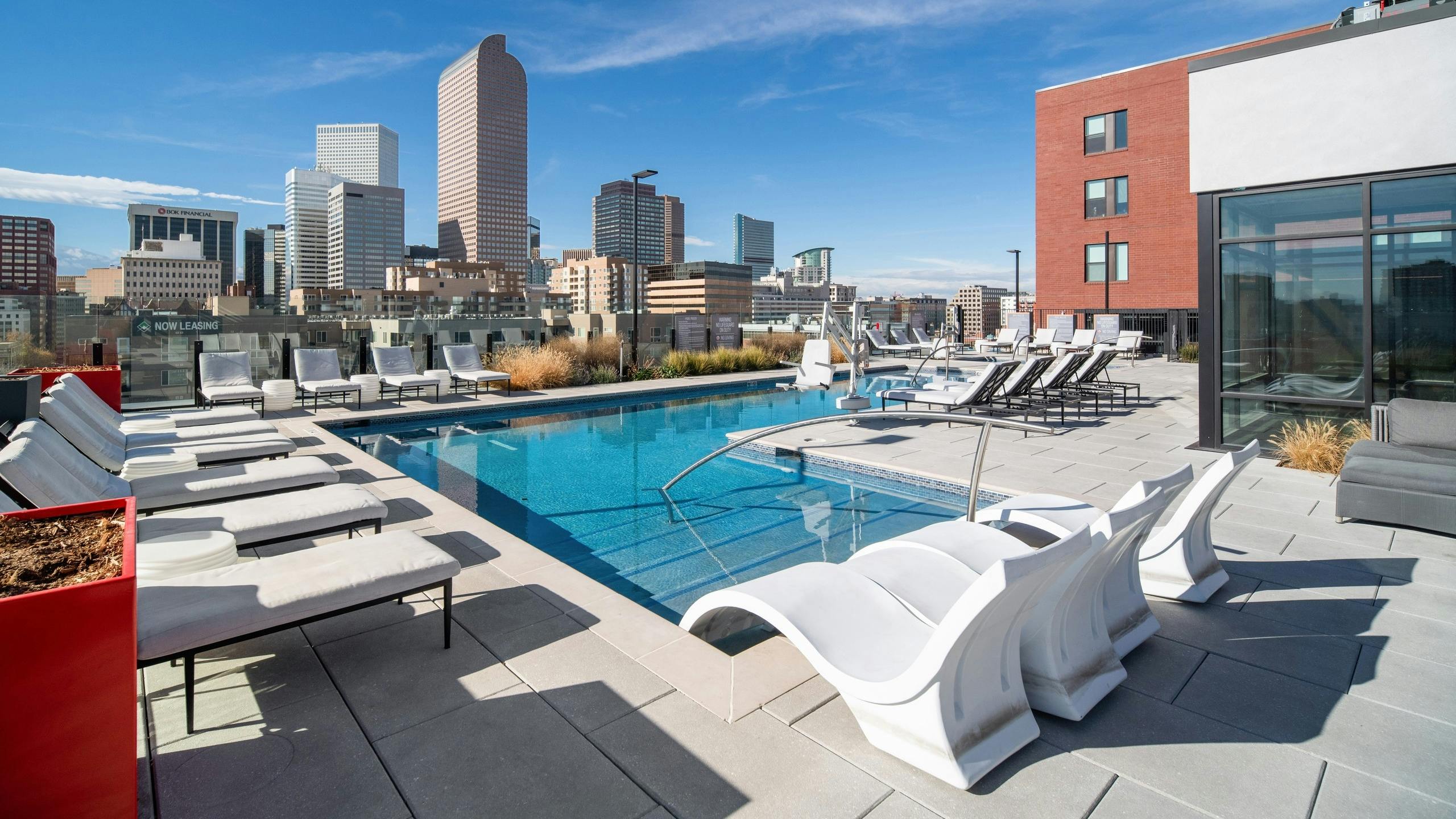 AMLI at Uptown rooftop pool lined by luxurious white lounge chairs and surrounded by tall city buildings in the daytime