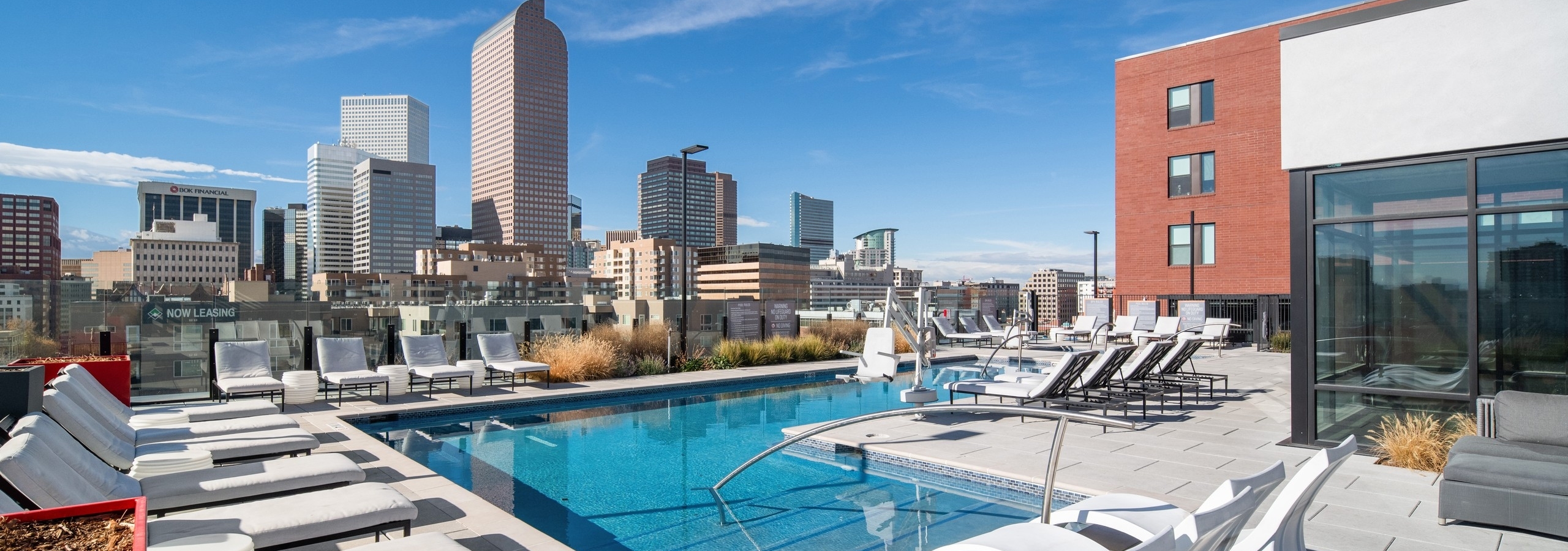 AMLI at Uptown rooftop pool lined by luxurious white lounge chairs and surrounded by tall city buildings in the daytime