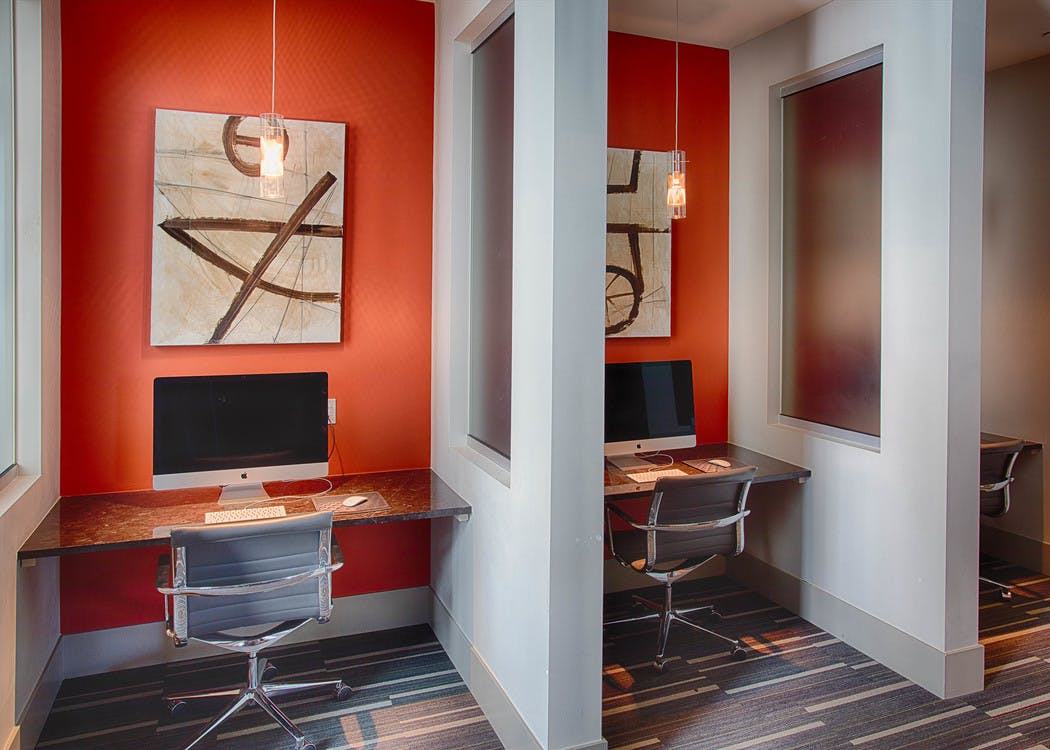 Business center at AMLI Denargo Market apartments with several desks and computers with rolling chairs and wall artwork