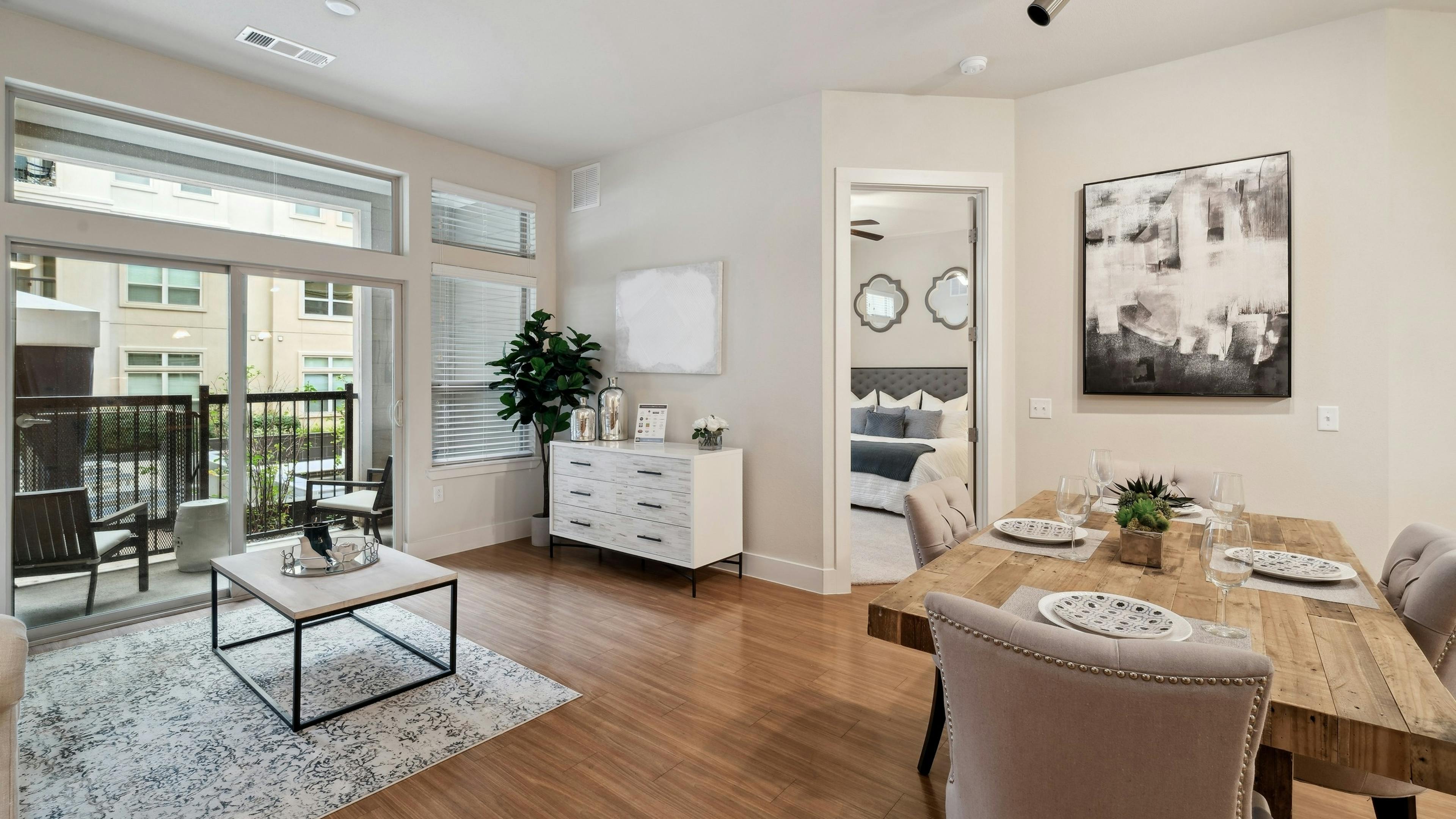 A dining and living room at AMLI RidgeGate with a wood dining table and a and a view into the bedroom and patio
