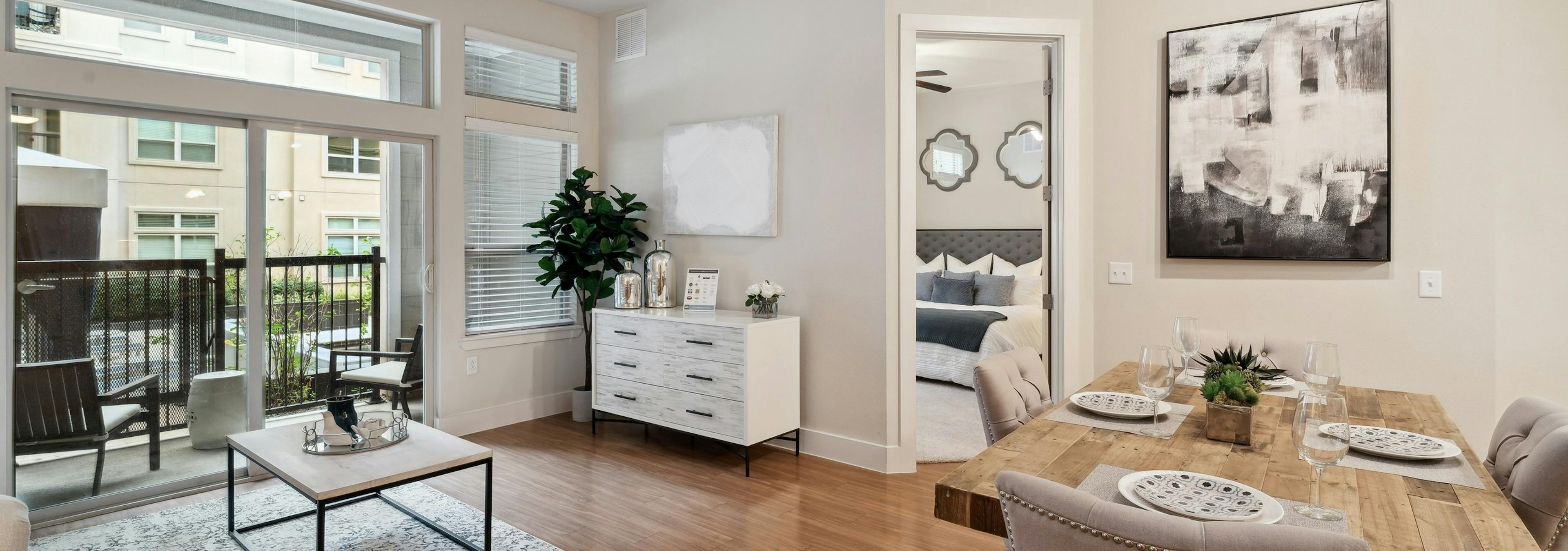 A dining and living room at AMLI RidgeGate with a wood dining table and a and a view into the bedroom and patio