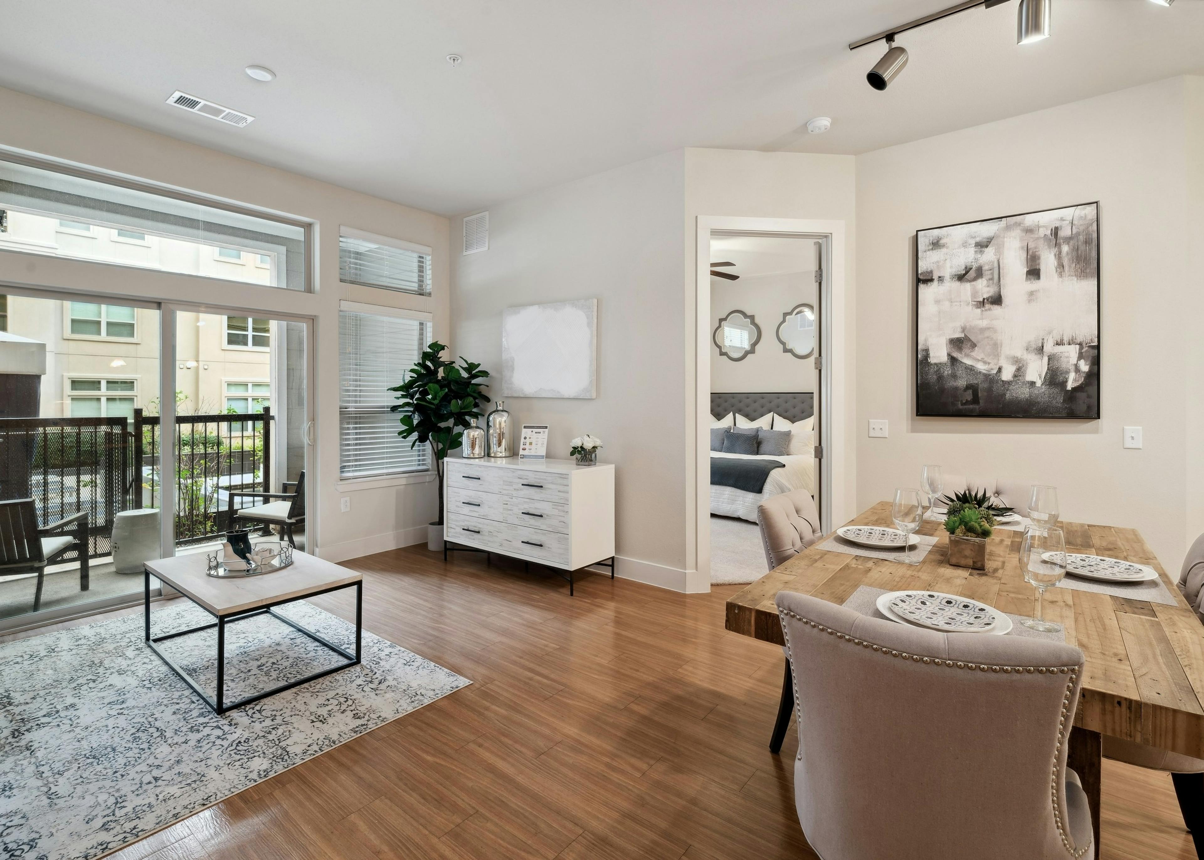 A dining and living room at AMLI RidgeGate with a wood dining table and a and a view into the bedroom and patio