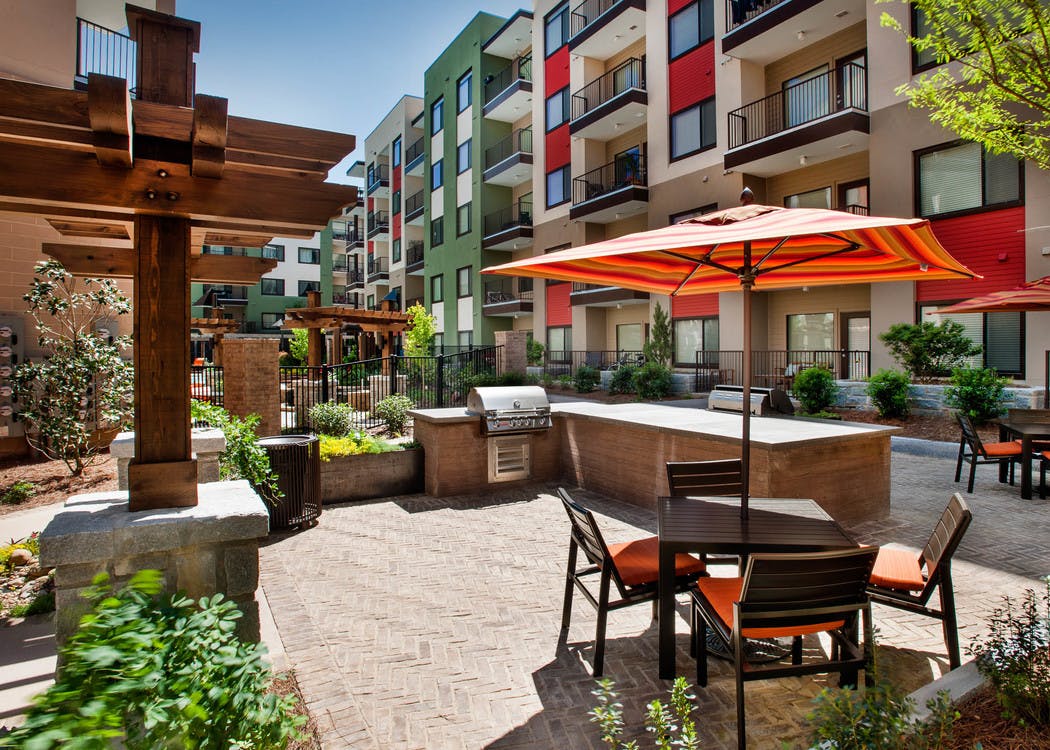 AMLI Ponce Park outdoor grilling area with stainless steel grill and counter space for food prep and a table with an umbrella