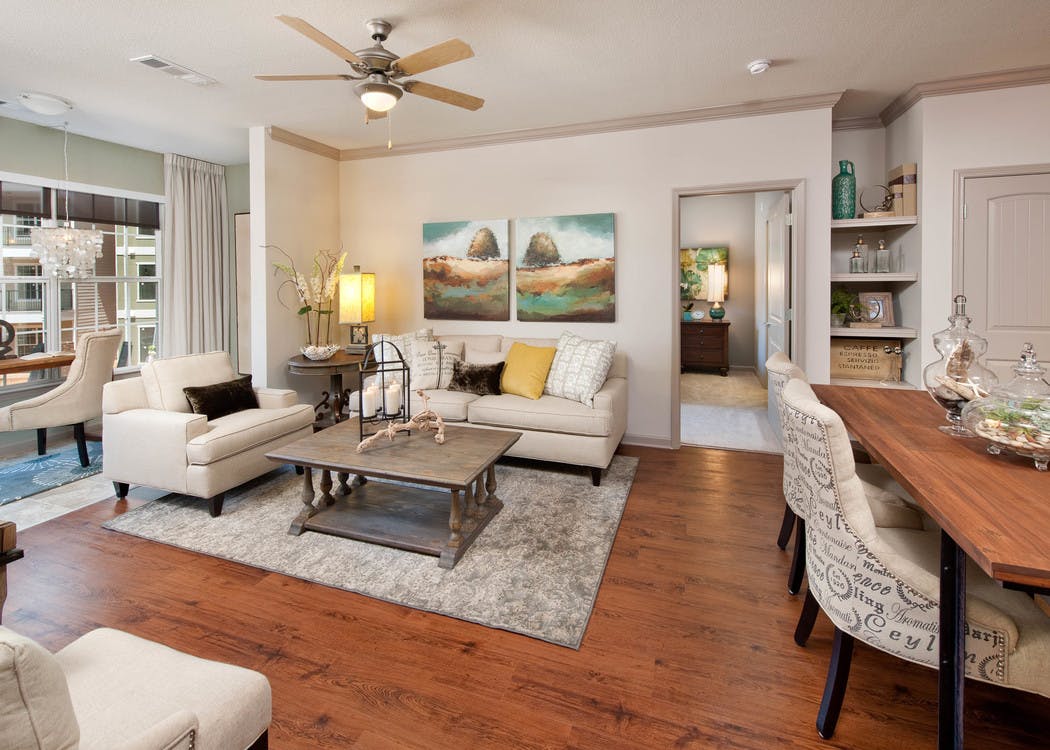 Living room at AMLI North Point with a large window and chestnut colored wood floors with neutral, elegant decor