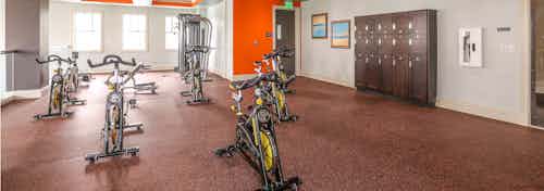 Interior of the spinning and yoga room at AMLI Doral with orange wall accent color and lockers