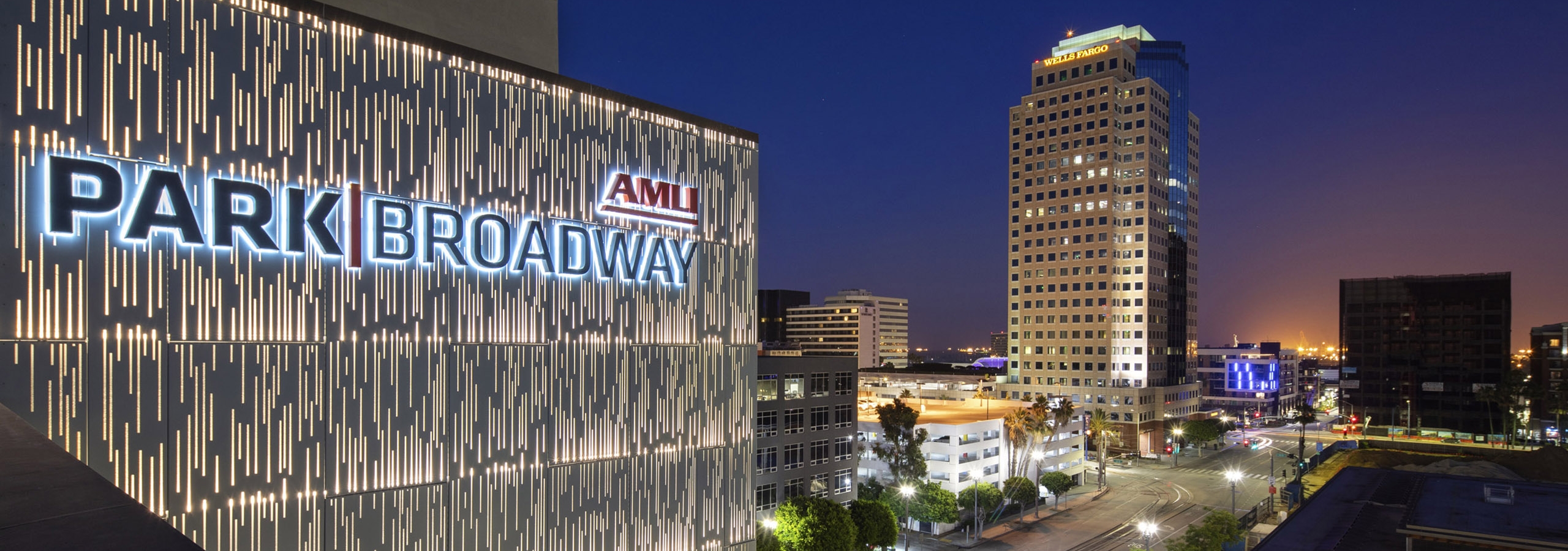 Aerial view of AMLI Park Broadway apartment building monument sign lit up with a view of lit street and city buildings