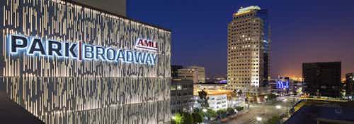 Aerial view of AMLI Park Broadway apartment building monument sign lit up with a view of lit street and city buildings