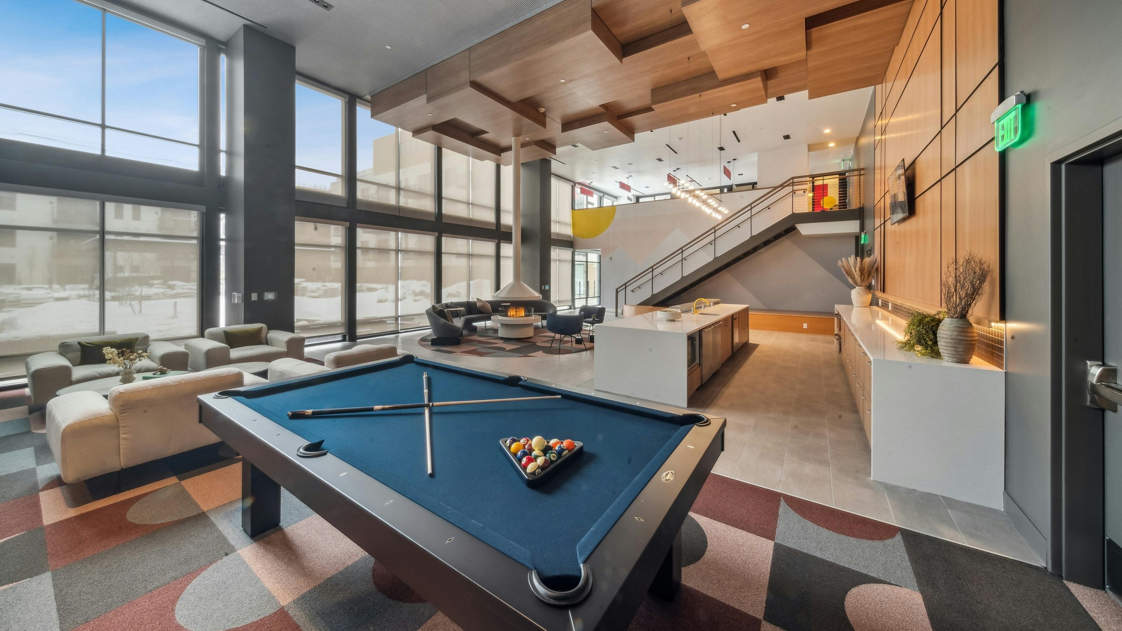 AMLI Broadway Park apartments resident lounge showcasing a billiards table and long bar and plush seating and tall fireplace 