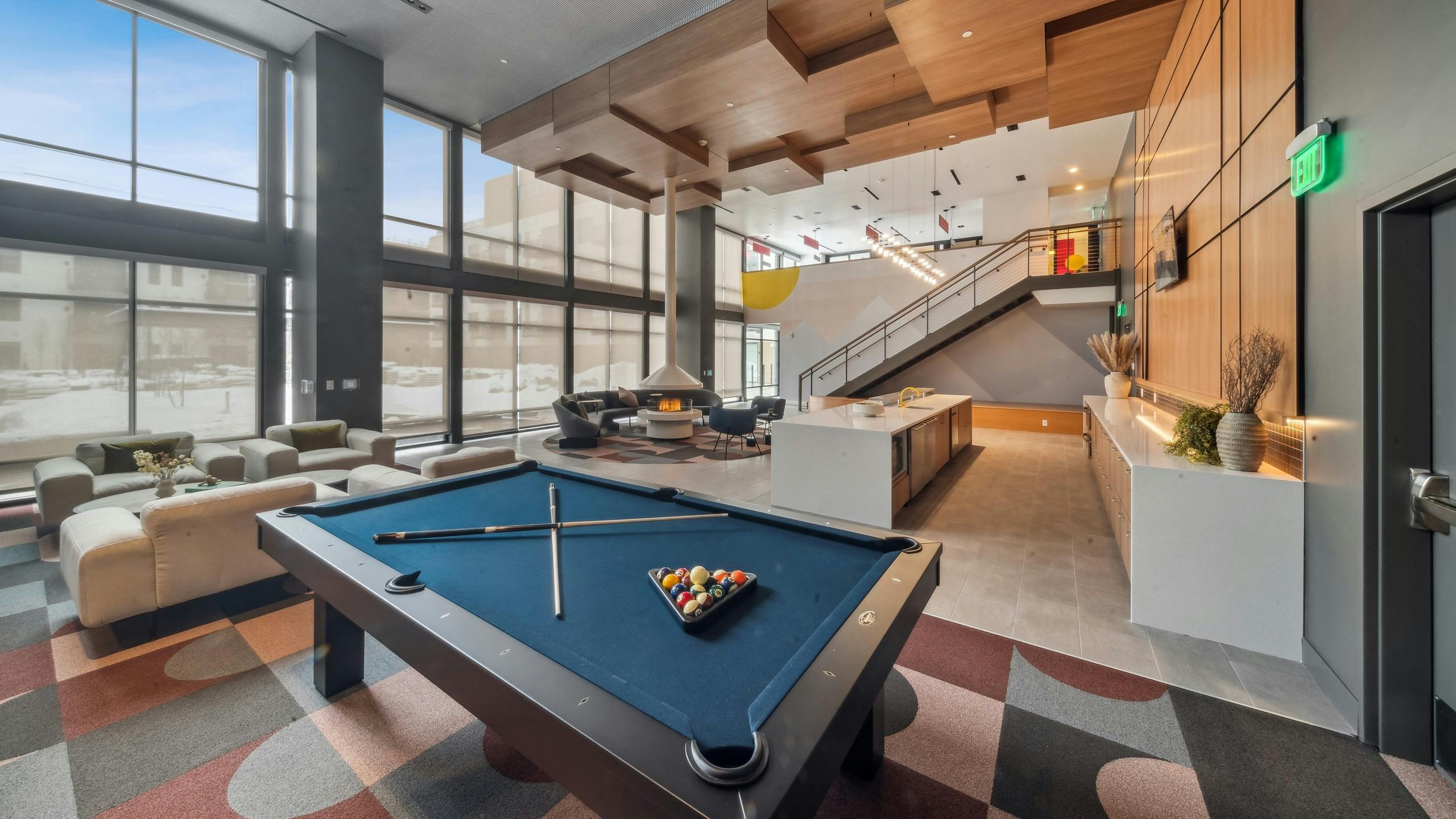AMLI Broadway Park apartments resident lounge showcasing a billiards table and long bar and plush seating and tall fireplace