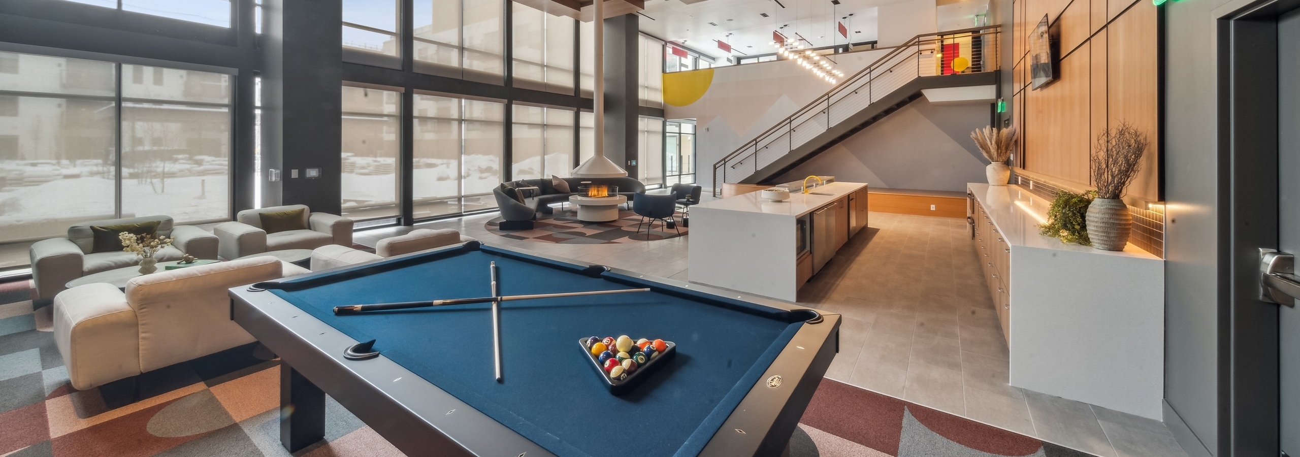 AMLI Broadway Park apartments resident lounge showcasing a billiards table and long bar and plush seating and tall fireplace