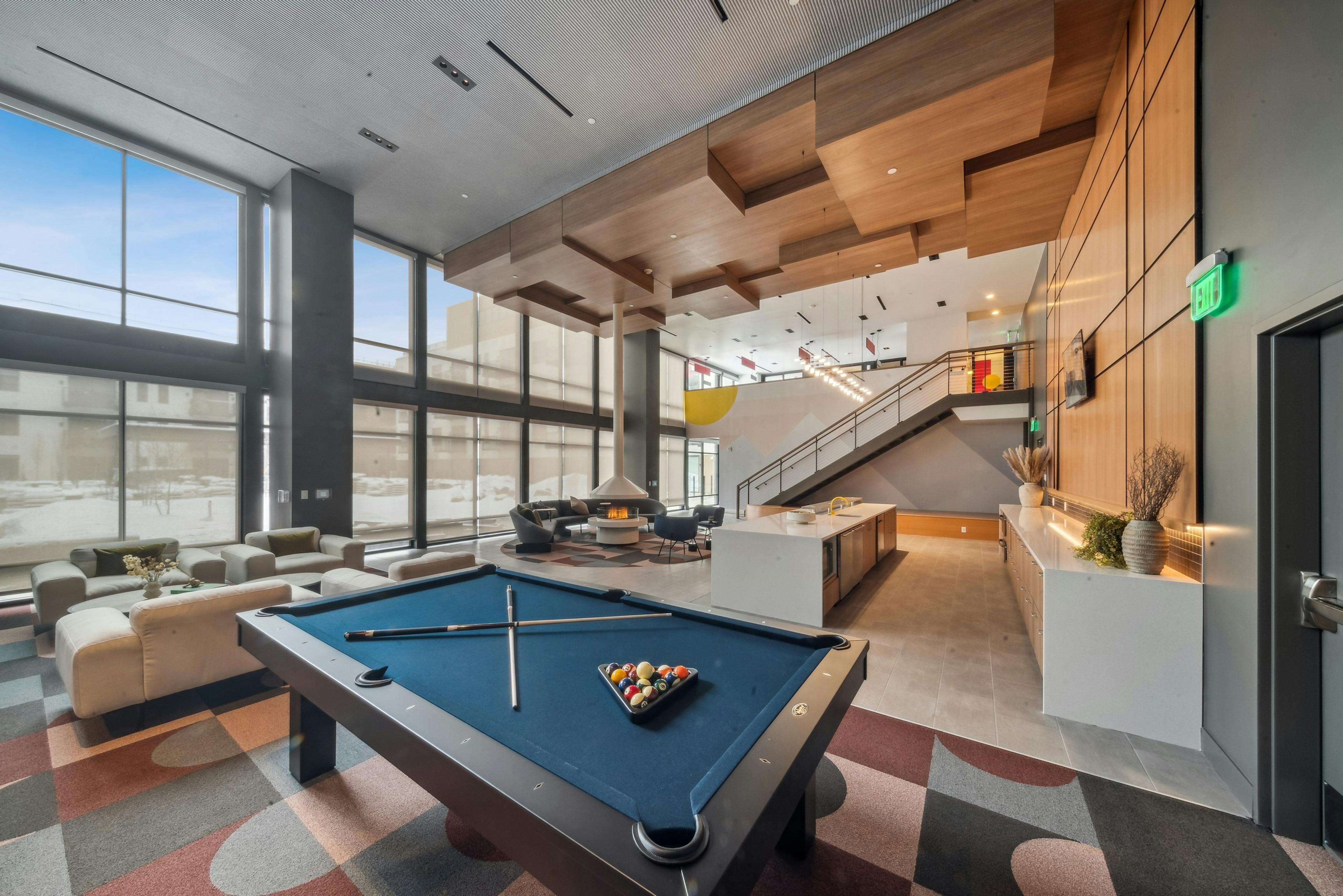 AMLI Broadway Park apartments resident lounge showcasing a billiards table and long bar and plush seating and tall fireplace 