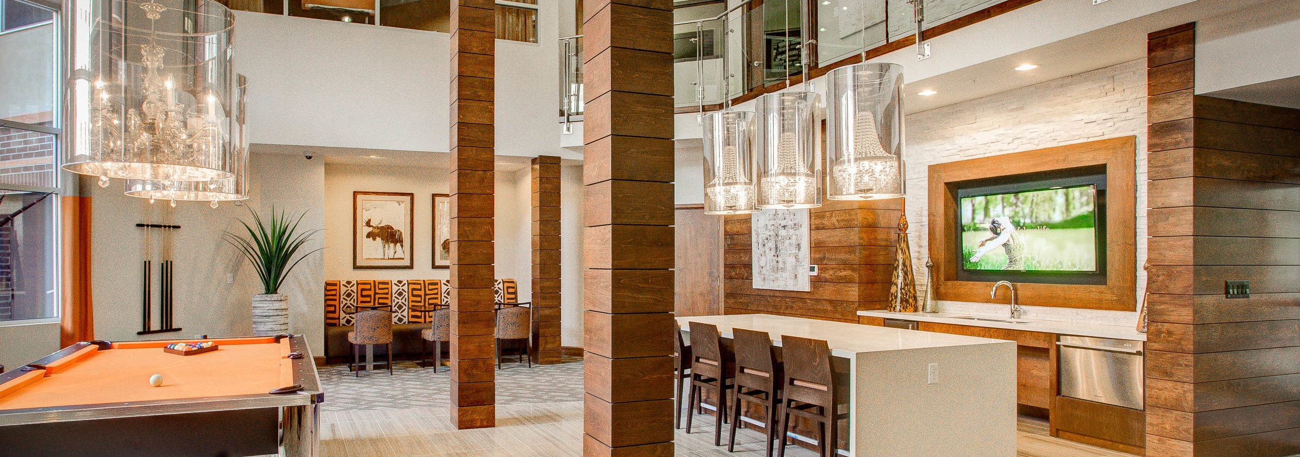 Interior view of the club room at AMLI Riverfront Park apartments with a pool table and television and a table with chairs
