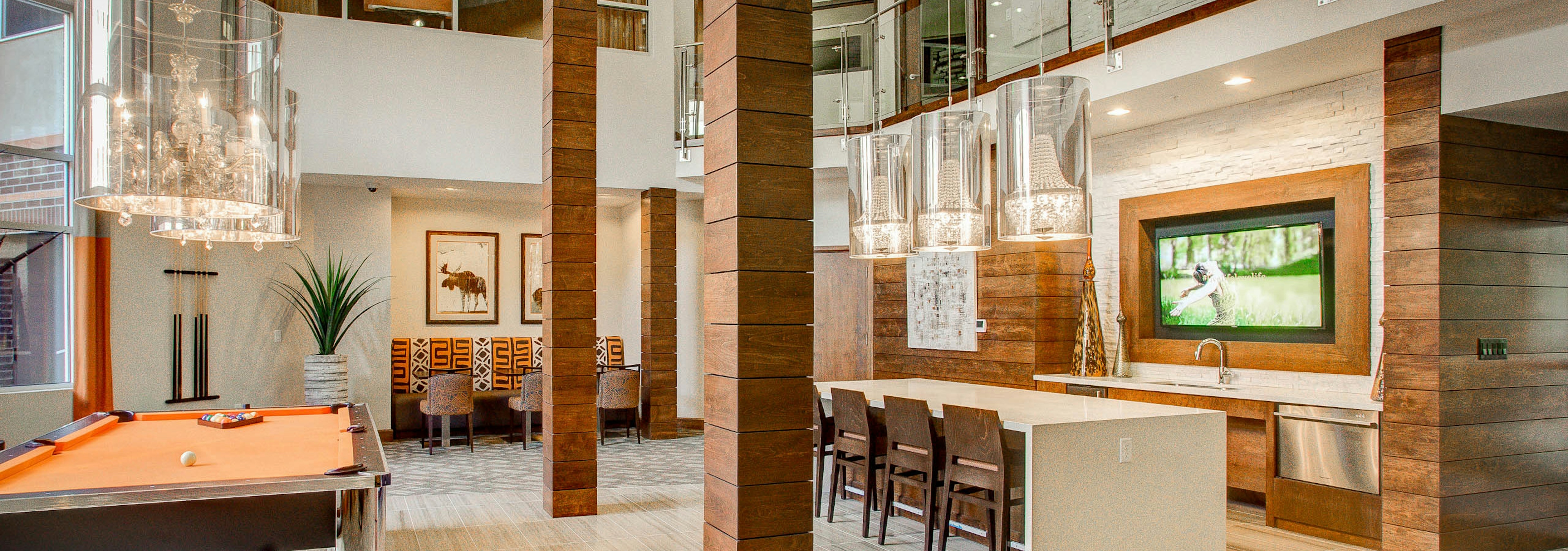 Interior view of the club room at AMLI Riverfront Park apartments with a pool table and television and a table with chairs