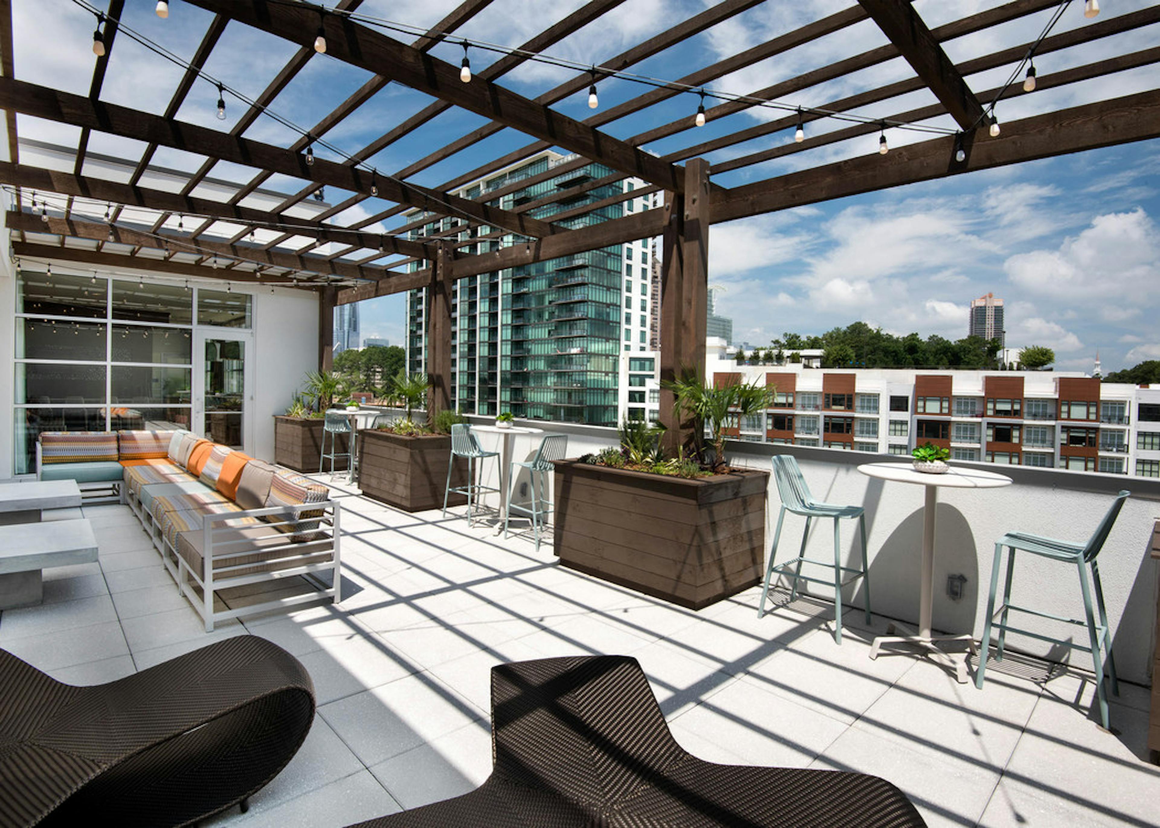 AMLI Buckhead apartment building skydeck with a bright daytime view showing long outdoor seating under a pergola 