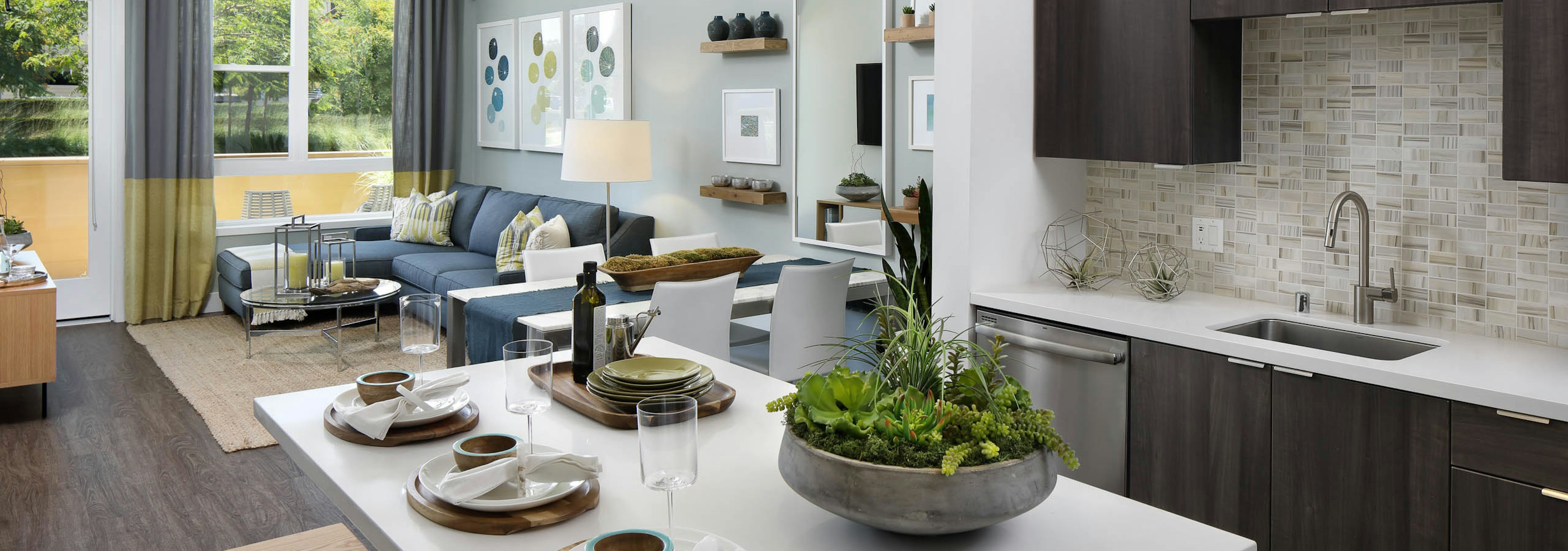 Interior of AMLI Uptown Orange apartment kitchen with dark wood cabinets and furnished living room with hard wood floors