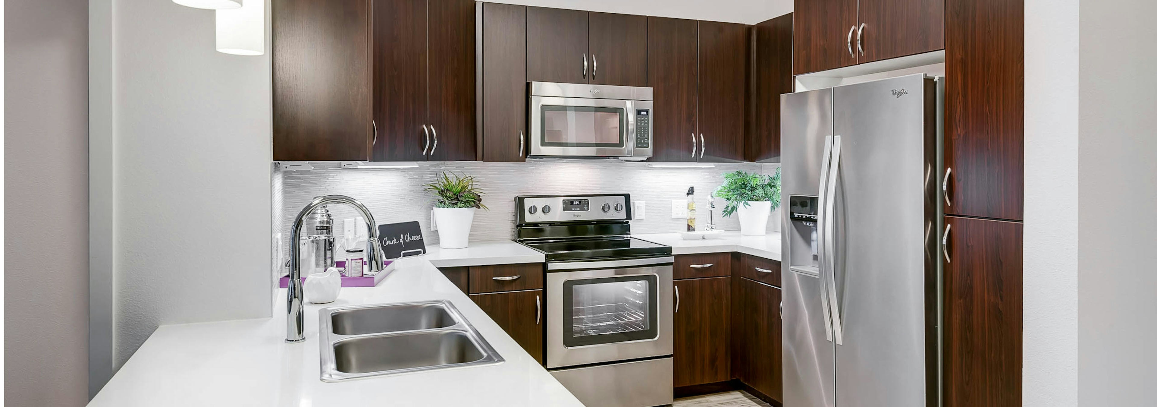 Interior view of a kitchen at AMLI Cherry Creek apartments with espresso colored cabinets and white granite counter tops