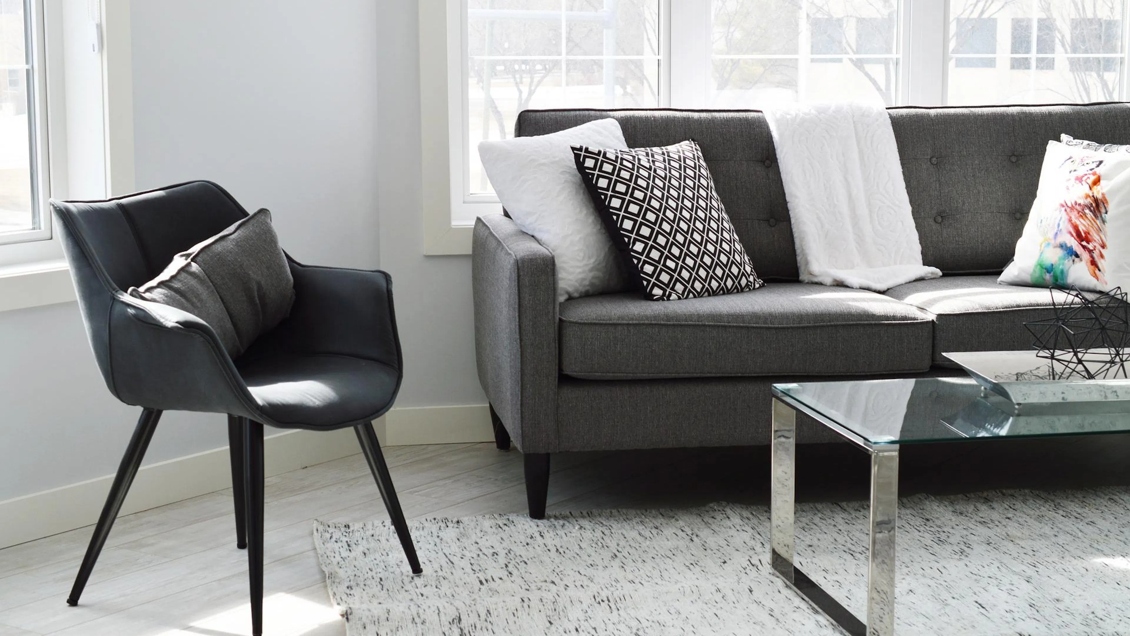 A black leather chair and a grey polyester sofa in a brightly lit living room