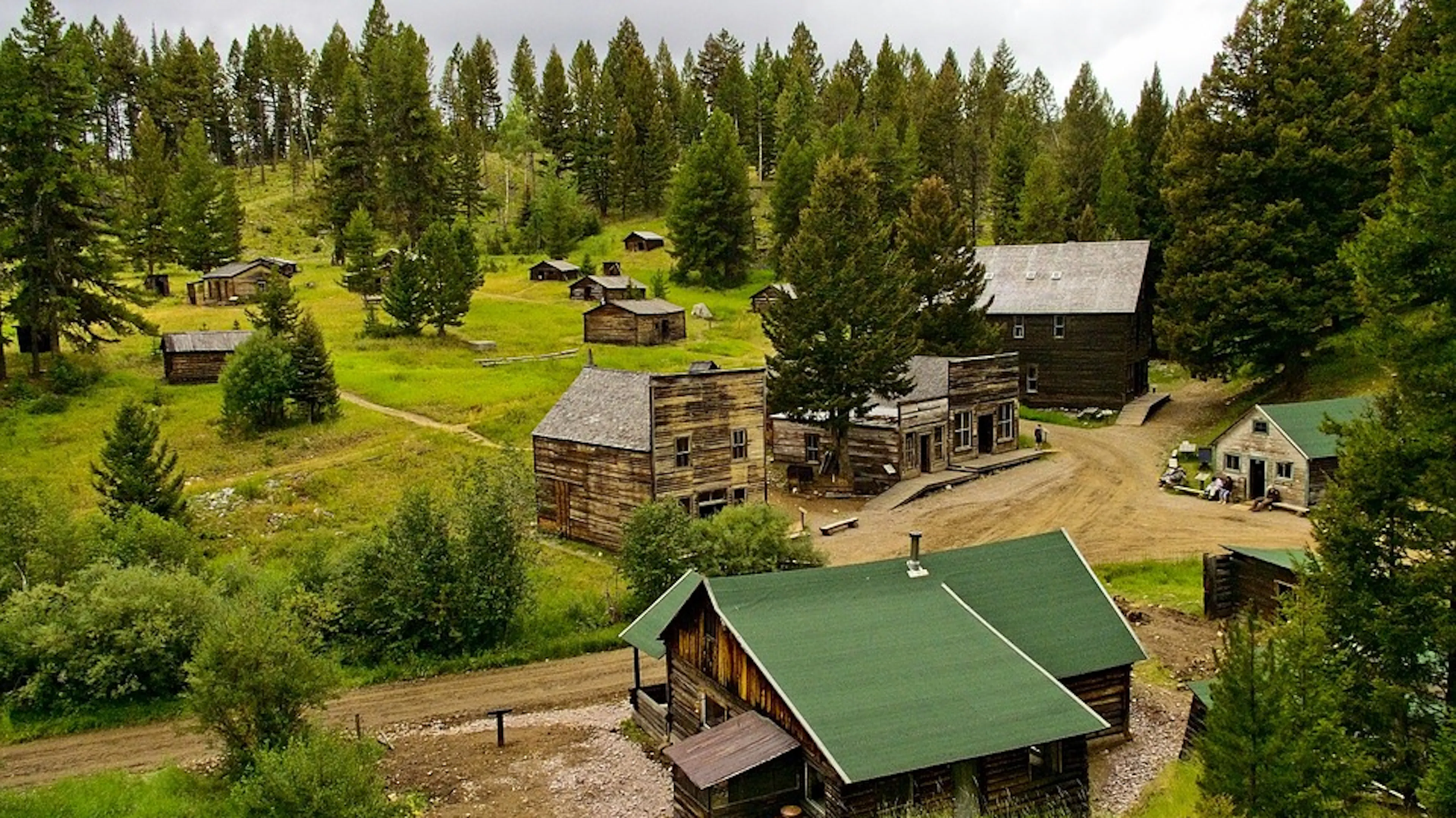 A collection of abandoned log cabins tucked away in a grassy mountain meadow