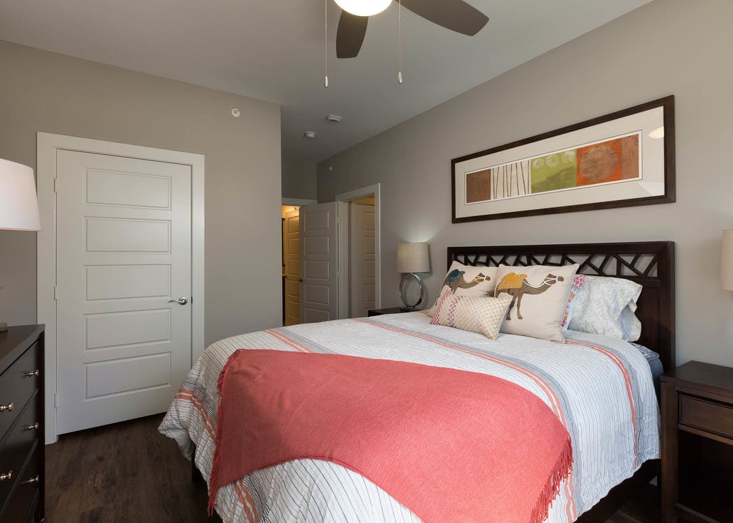 An interior view of AMLI Covered Bridge bedroom with a 5 panel bedroom door and a ceiling fan