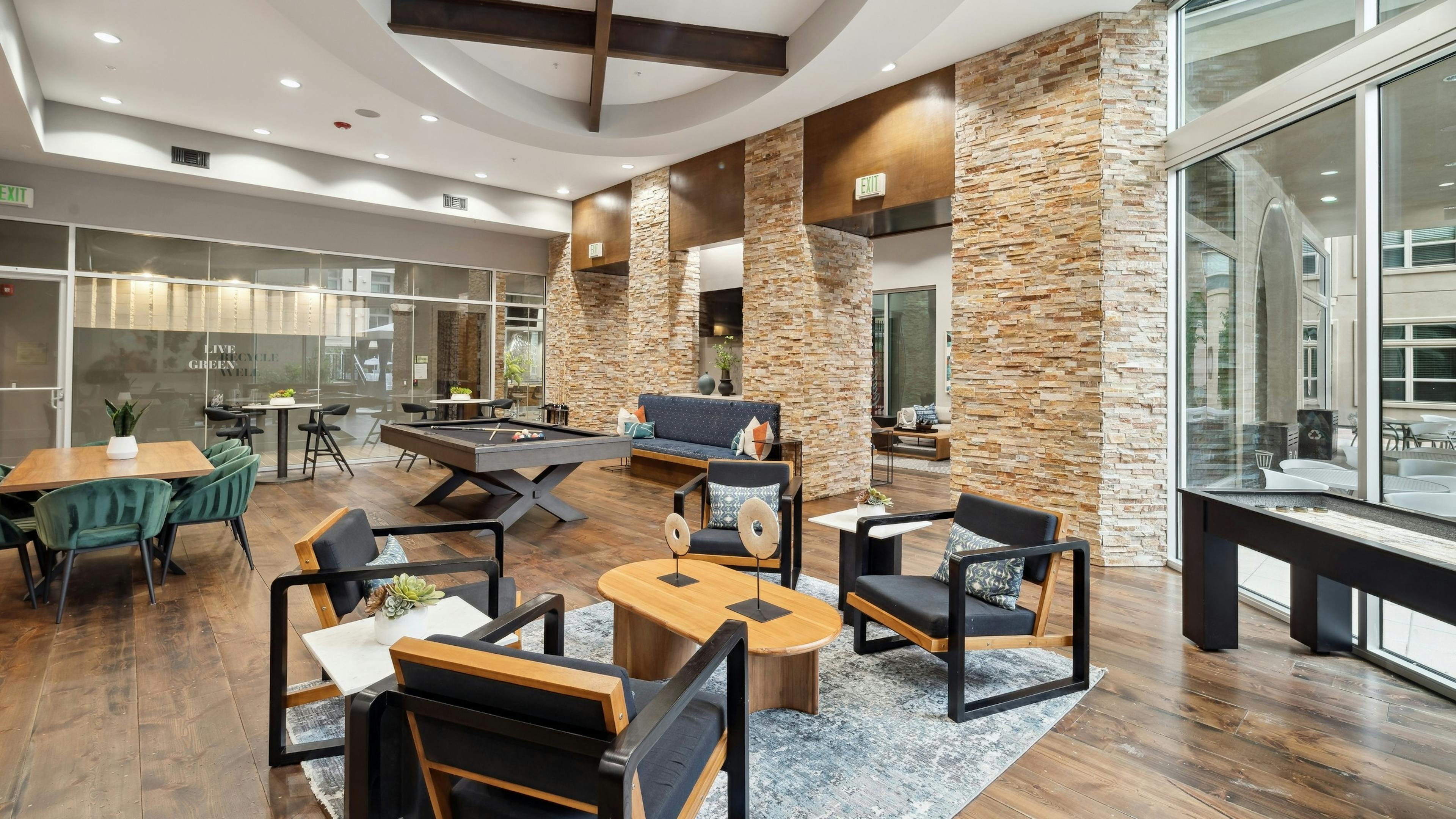 Interior view of a resident lounge at AMLI RidgeGate with a pool table and shuffleboard and tables and chairs with pillows