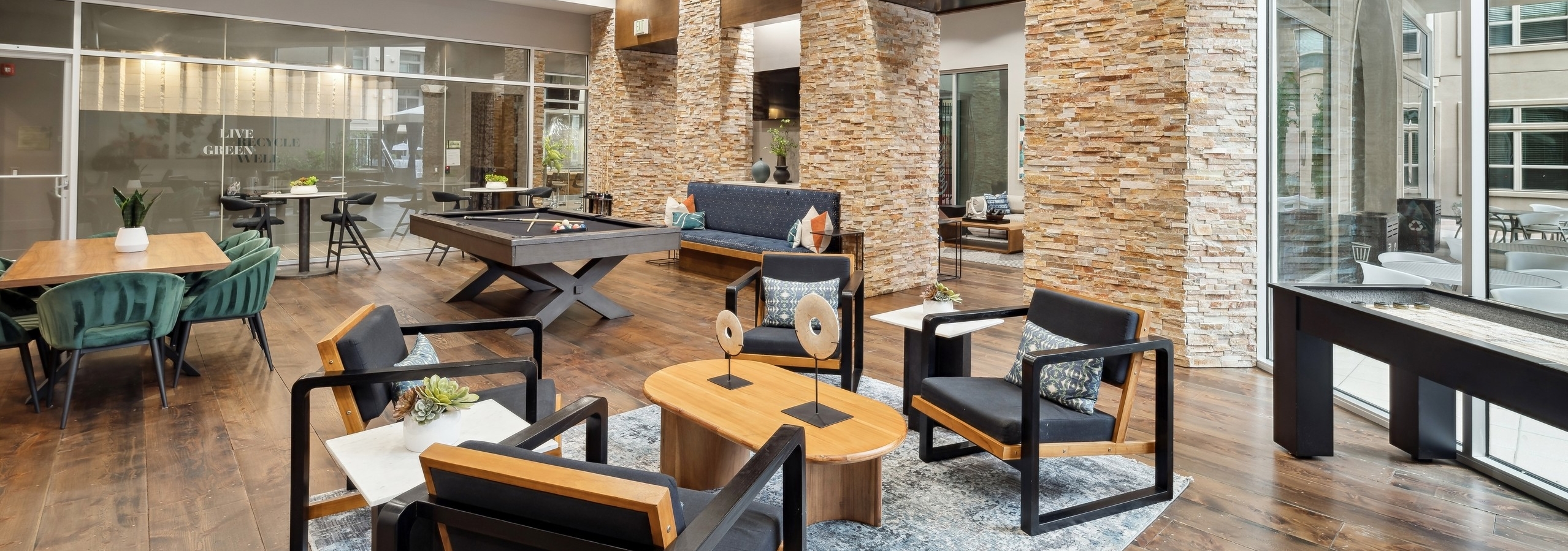 Interior view of a resident lounge at AMLI RidgeGate with a pool table and shuffleboard and tables and chairs with pillows