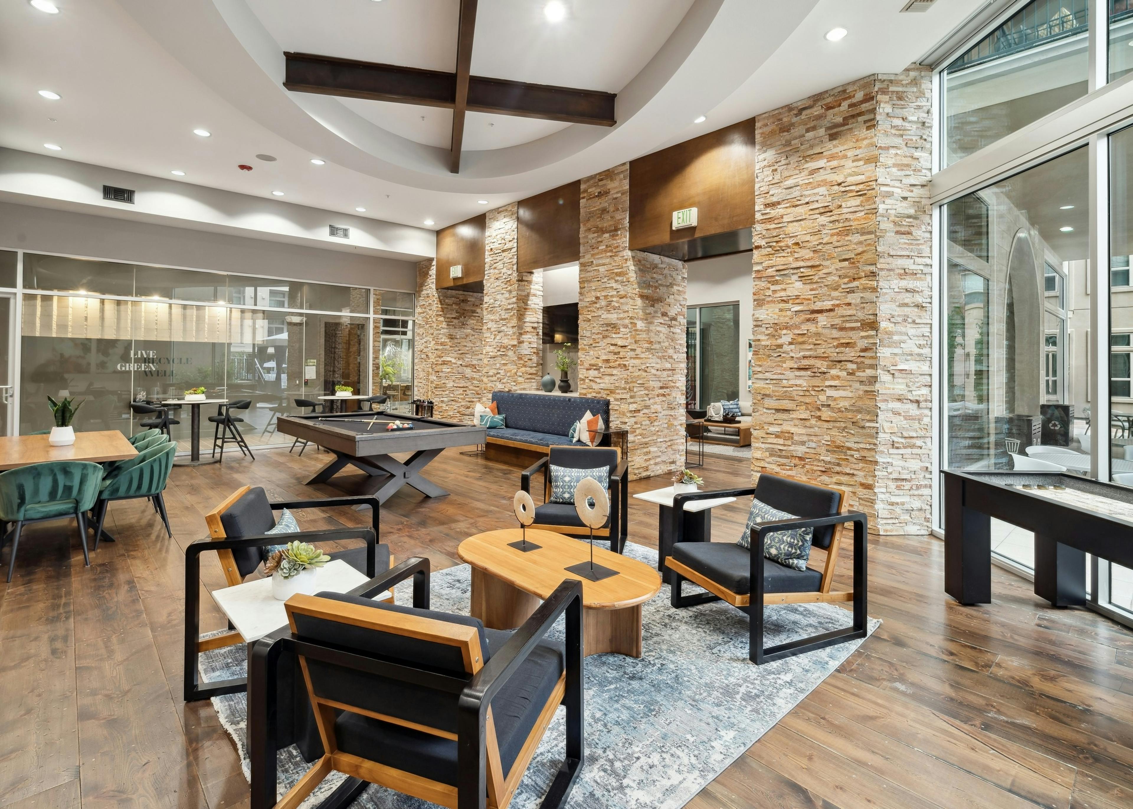 Interior view of a resident lounge at AMLI RidgeGate with a pool table and shuffleboard and tables and chairs with pillows