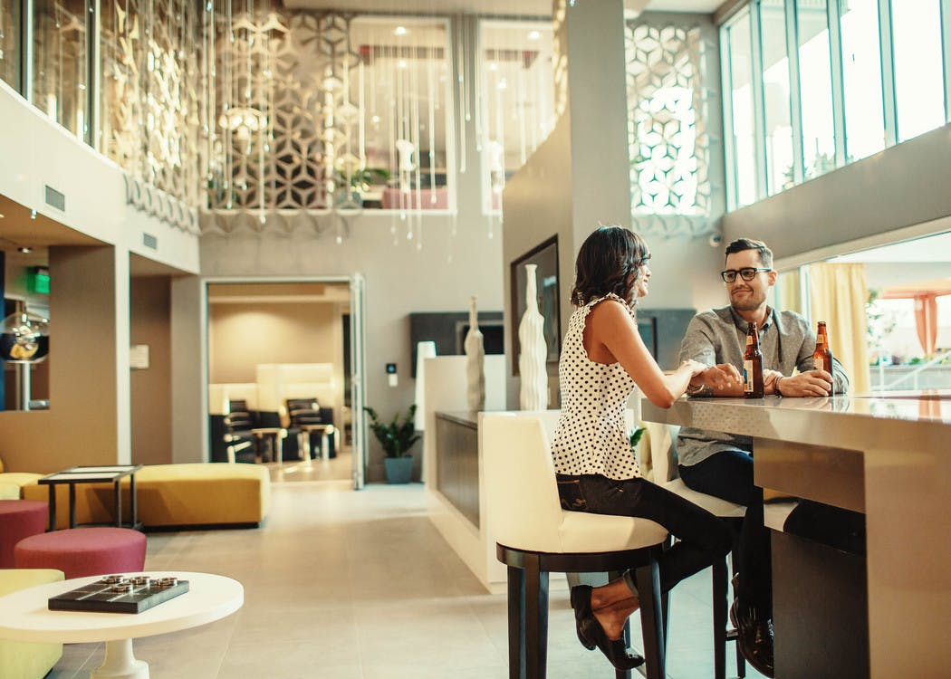 Interior of clubhouse at AMLI Lex on Orange apartments with tall ceilings and a happy couple sitting at the bar and chatting